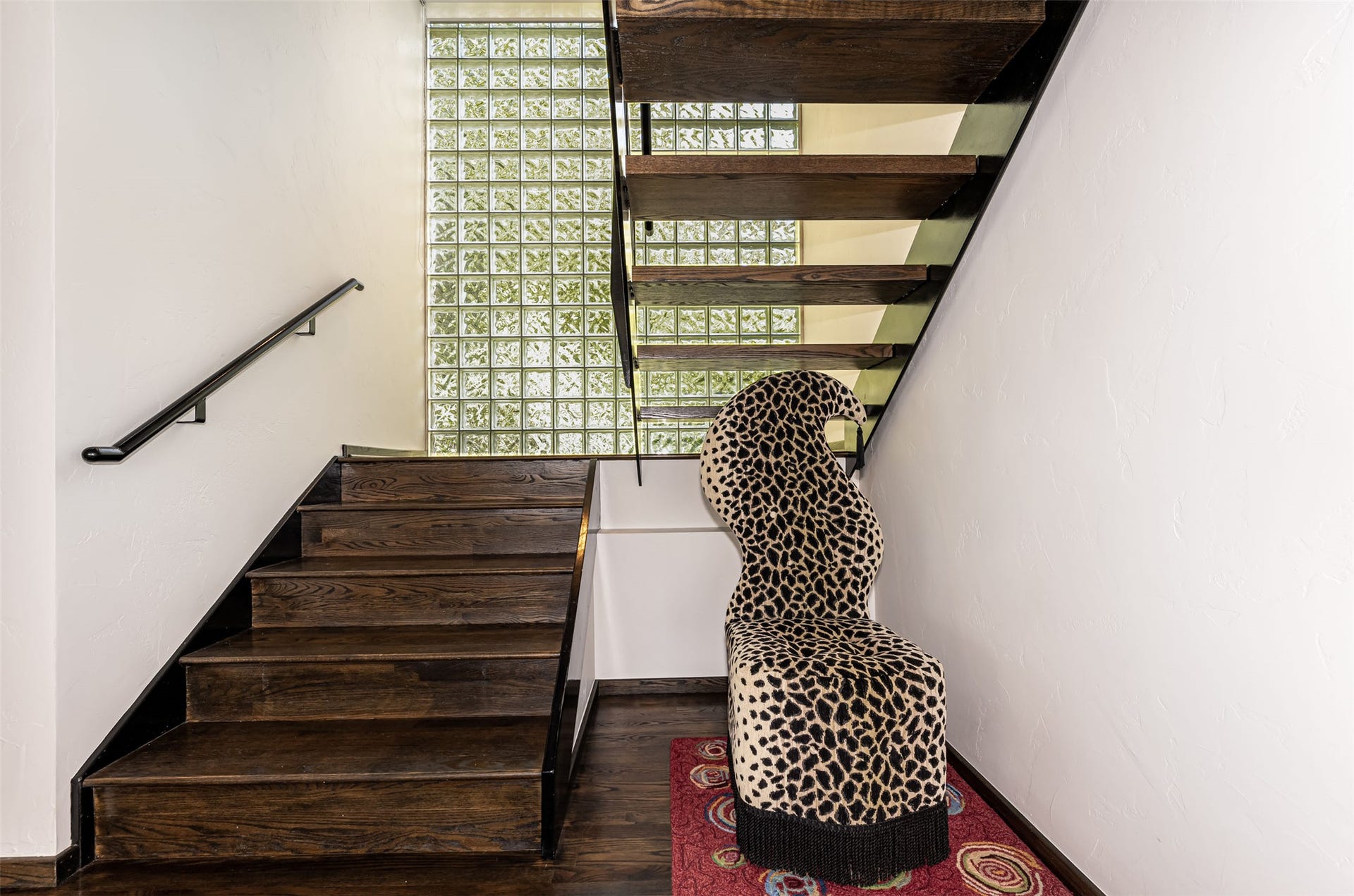 Wood-finish staircase with black risers and a black metal handrail