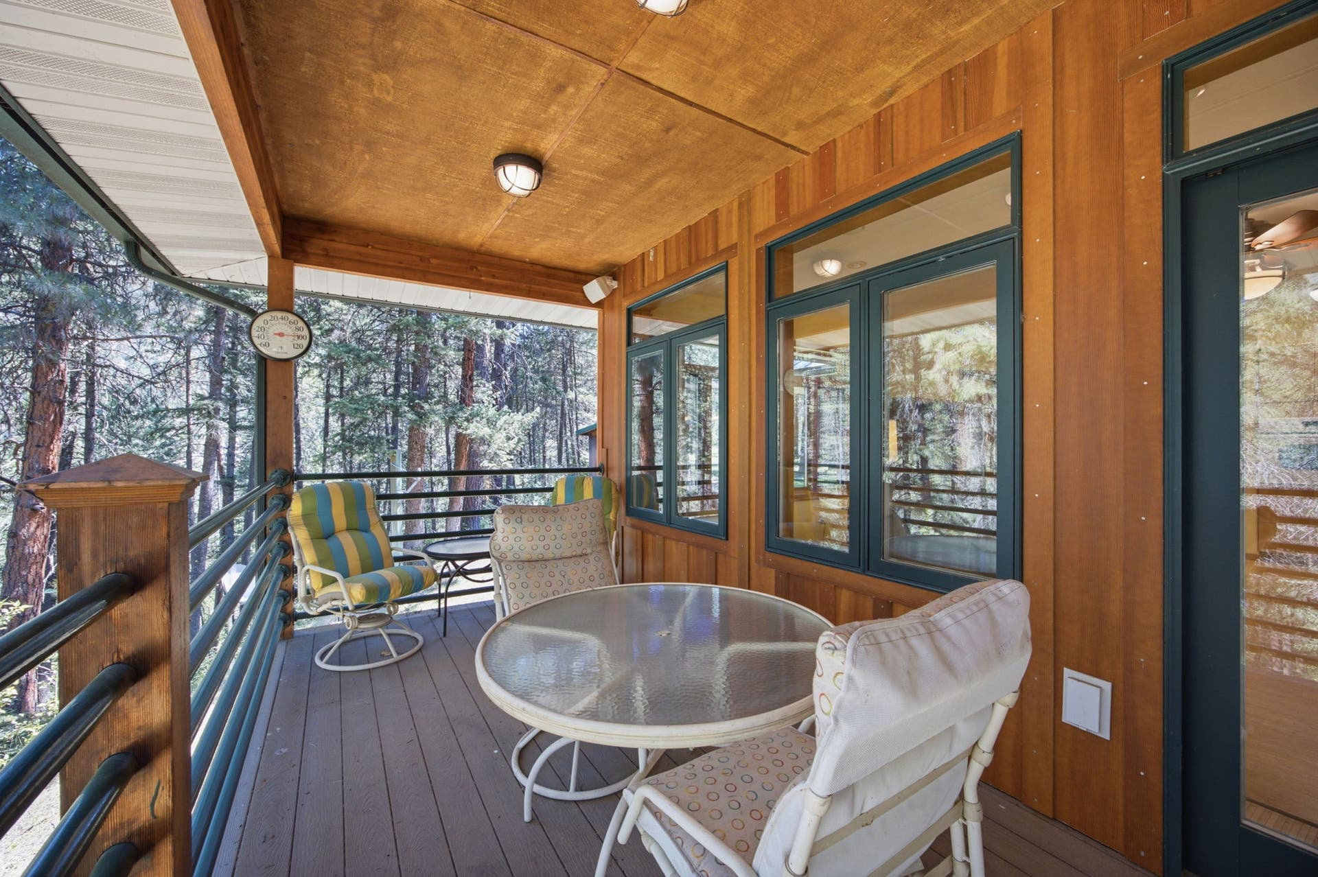 Designed to maximize indoor-outdoor living, this additional covered seating area provides a comfortable retreat surrounded by towering pines, perfect for quiet mornings, afternoon gatherings, or relaxing evenings.