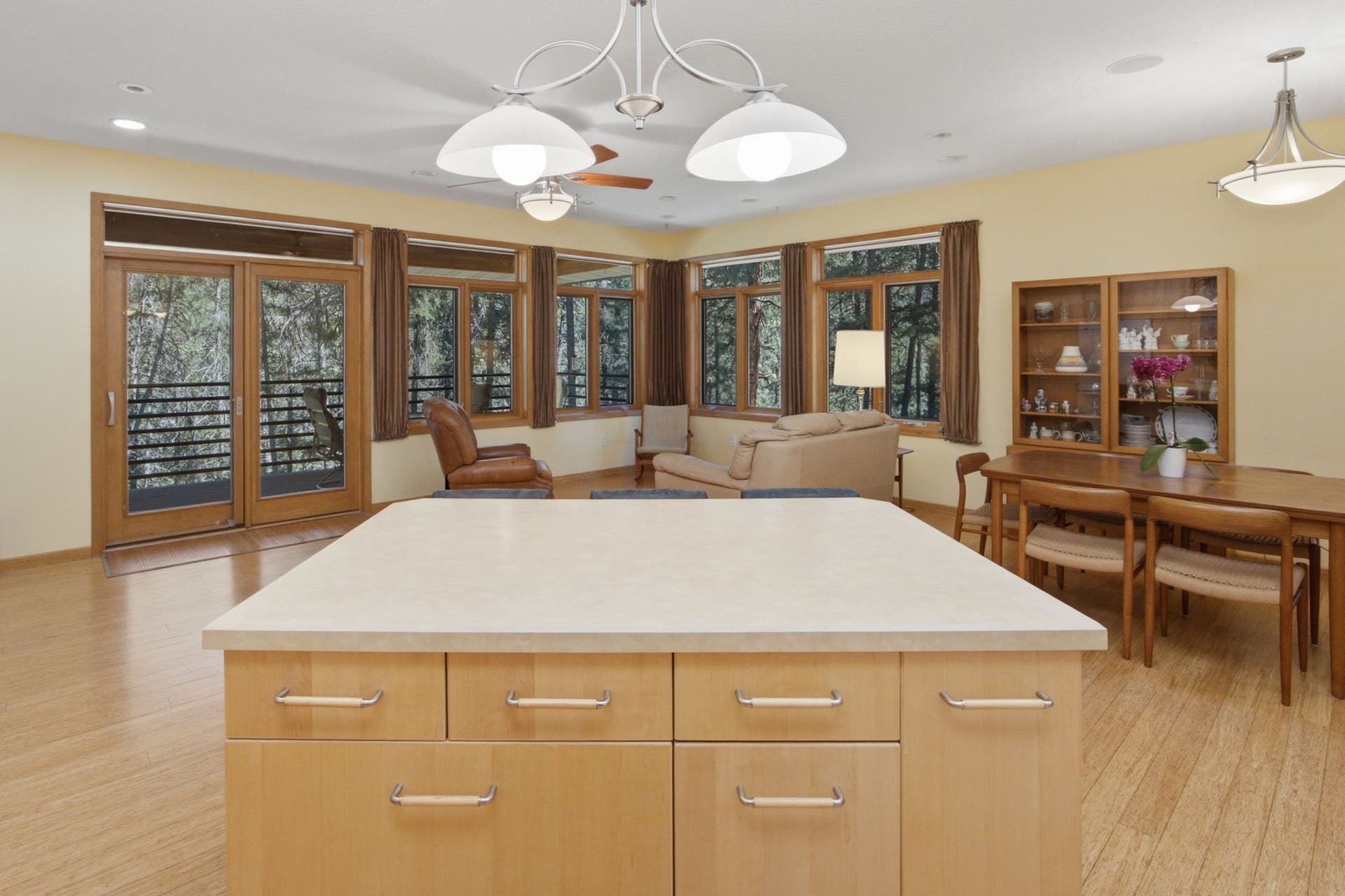 Looking back across the kitchen and dining area, the open design, soaring ceilings, and beautiful bamboo flooring create a warm, welcoming space that is equally suited for quiet mornings or larger gatherings.