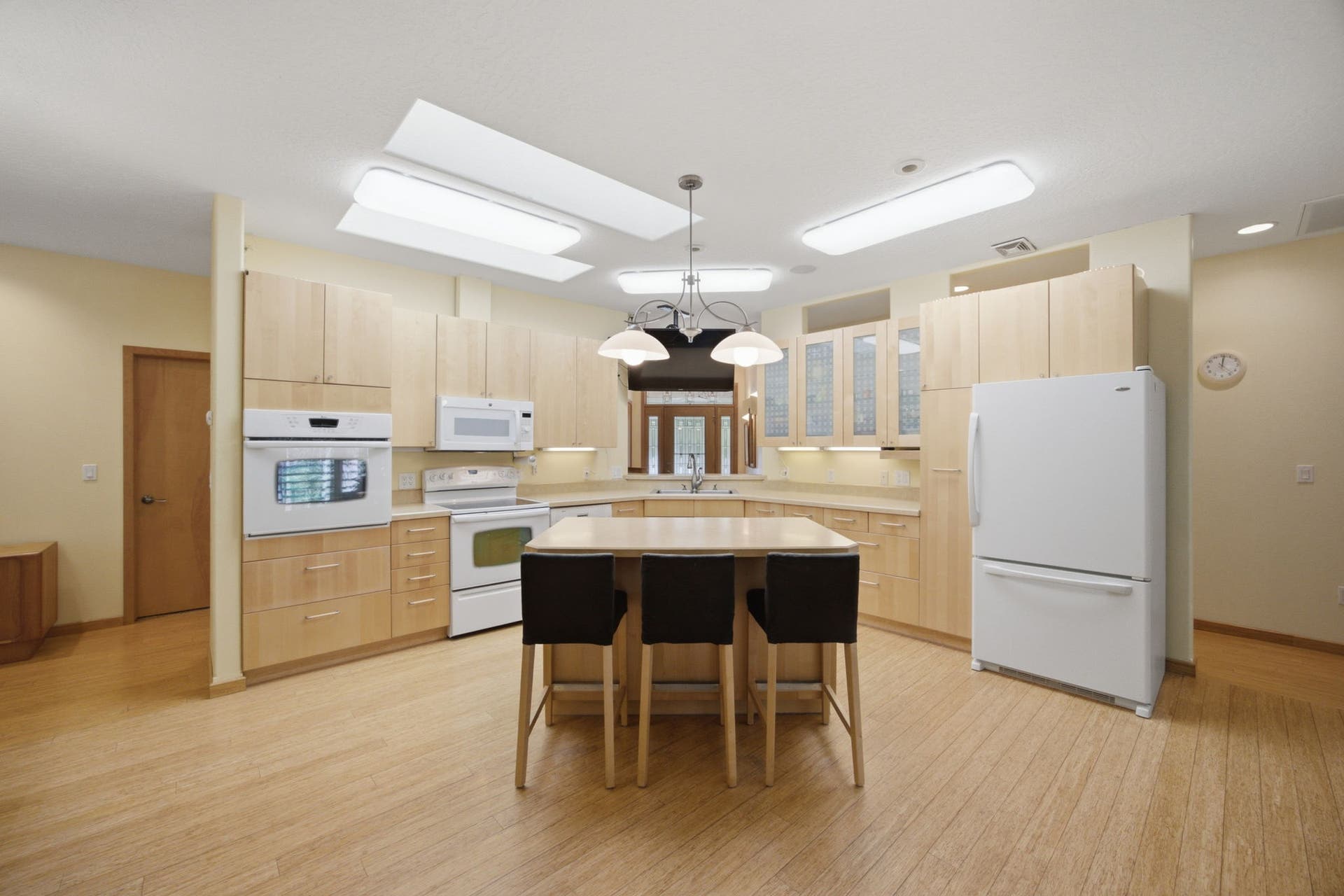 A spacious kitchen is illuminated by large skylights overhead, filling the space with natural light. An oversized center island provides ample workspace and seating for gathering with family and friends.