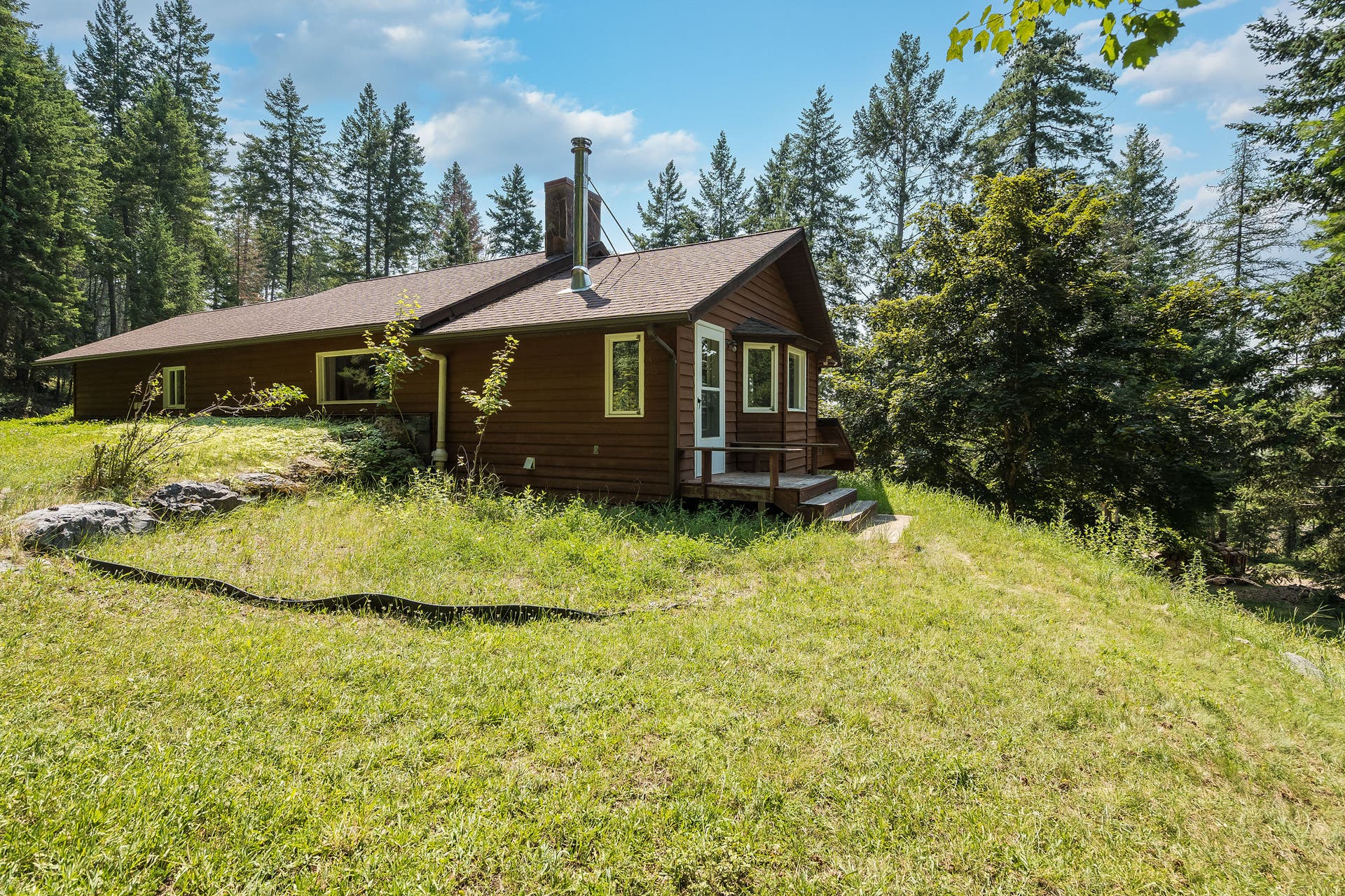 244 Bench Drive, Kalispell, MT 59901 Exterior view of 1980s wood-sided home on 3 acres with no HOA in Kalispell Montana.