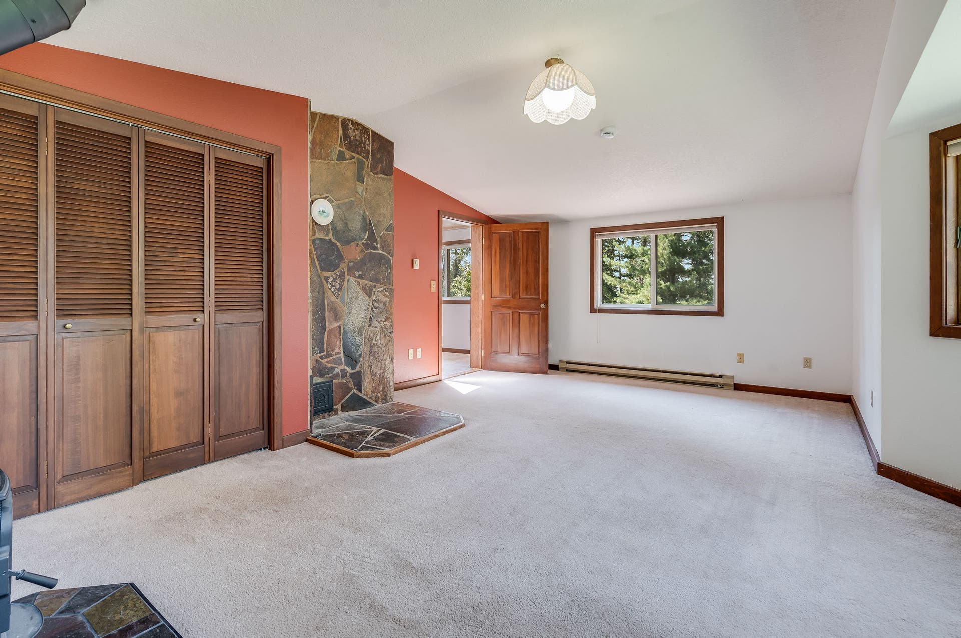 244 Bench Drive, Kalispell, MT 59901 Spacious primary bedroom with wood accents and natural lighting in Kalispell real estate listing. Generous primary bedroom with updated stove and plenty of natural light.