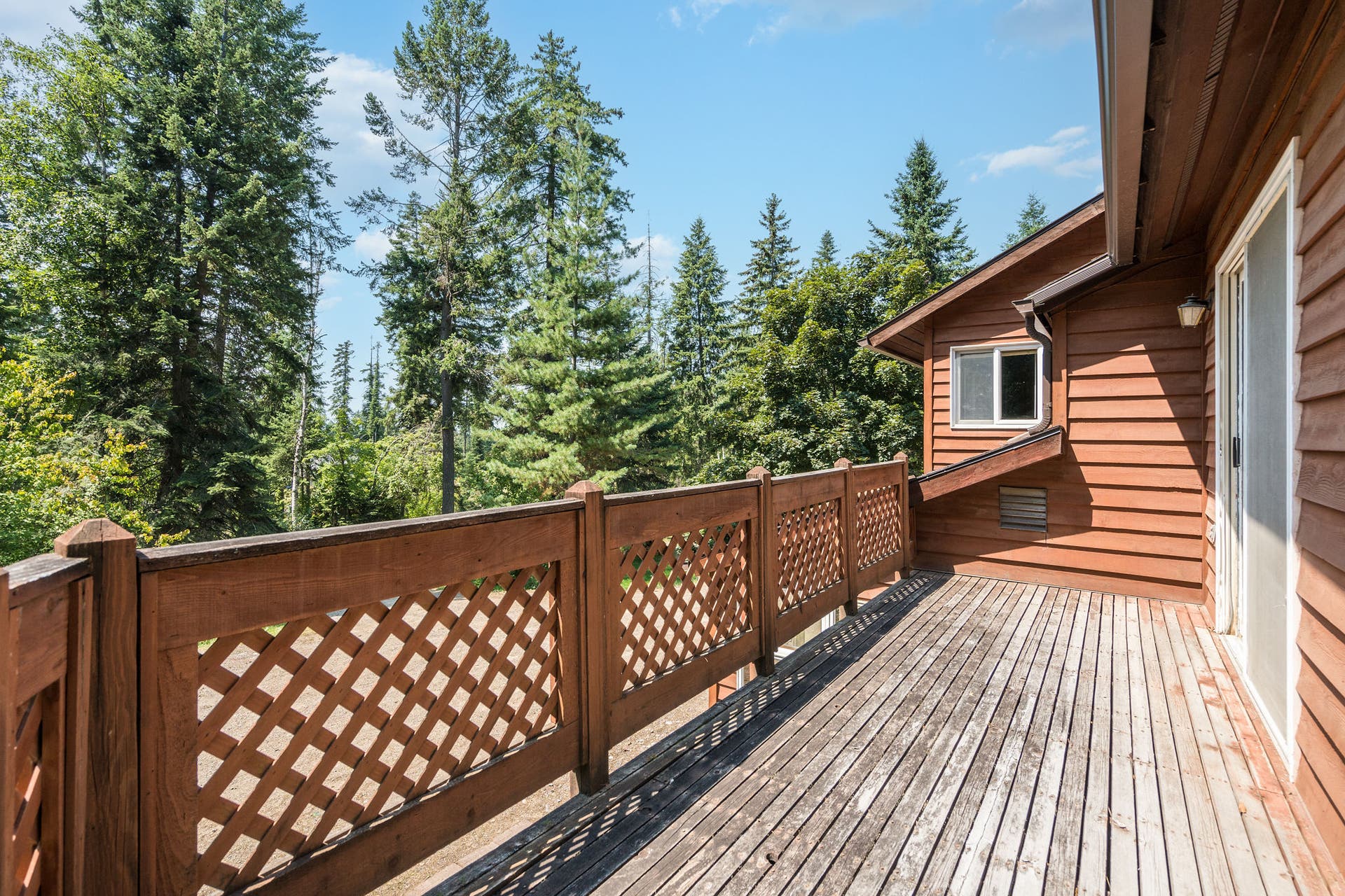 244 Bench Drive, Kalispell, MT 59901 Exterior view of 1980s wood-sided home with deck on 3 acres with no HOA in Kalispell Montana.