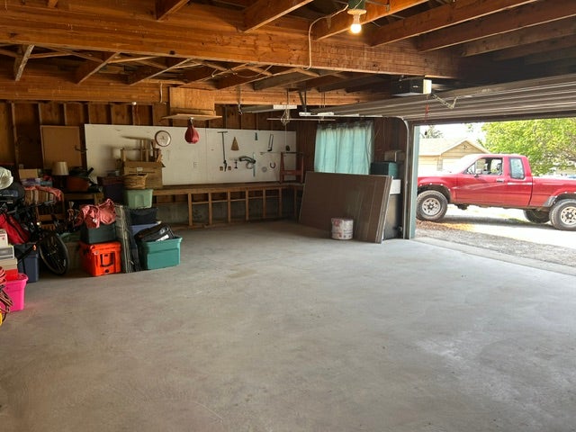 Private alley access to this spacious garage featuring exposed wood beam ceiling, concrete flooring, a built-in workbench, and overhead lighting