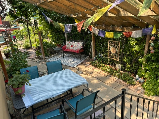 Patio area featuring a wood pergola, brick paver hardscaping, and lush perimeter landscaping.  A bird's paradise