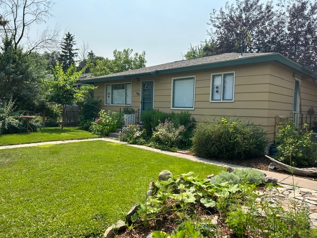 Front exterior with plum trees, choke cherry tree, crabapple tree, goji berry bush and mature flower beds.