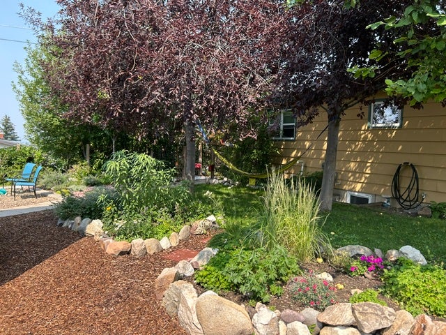 Landscaped back yard featuring a wood chip pathway and a stone-lined garden bed
