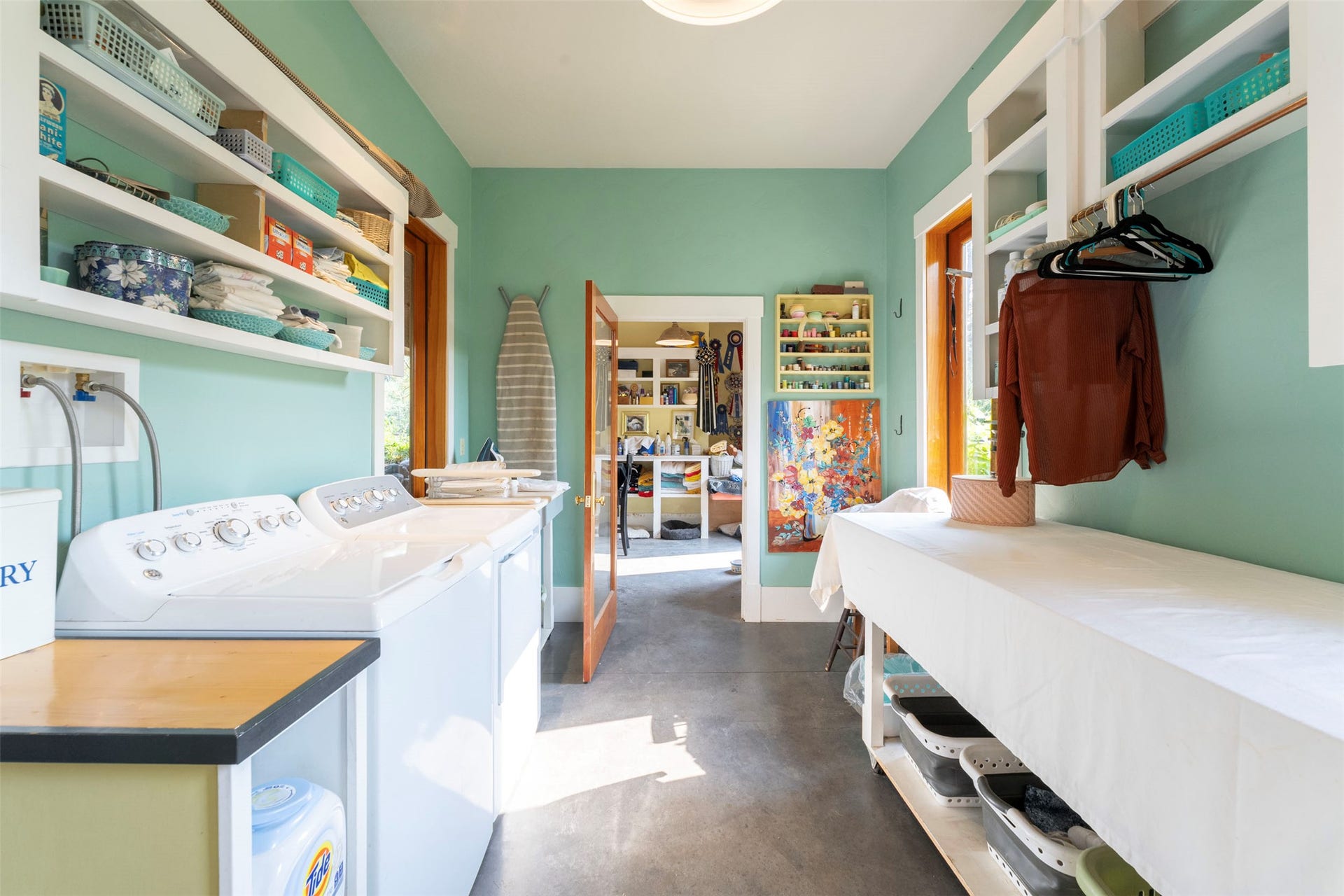 21848 Mt Highway 35, Bigfork, MT 59911 Bright laundry room featuring soft green walls, abundant natural light, and extensive built-in storage throughout.