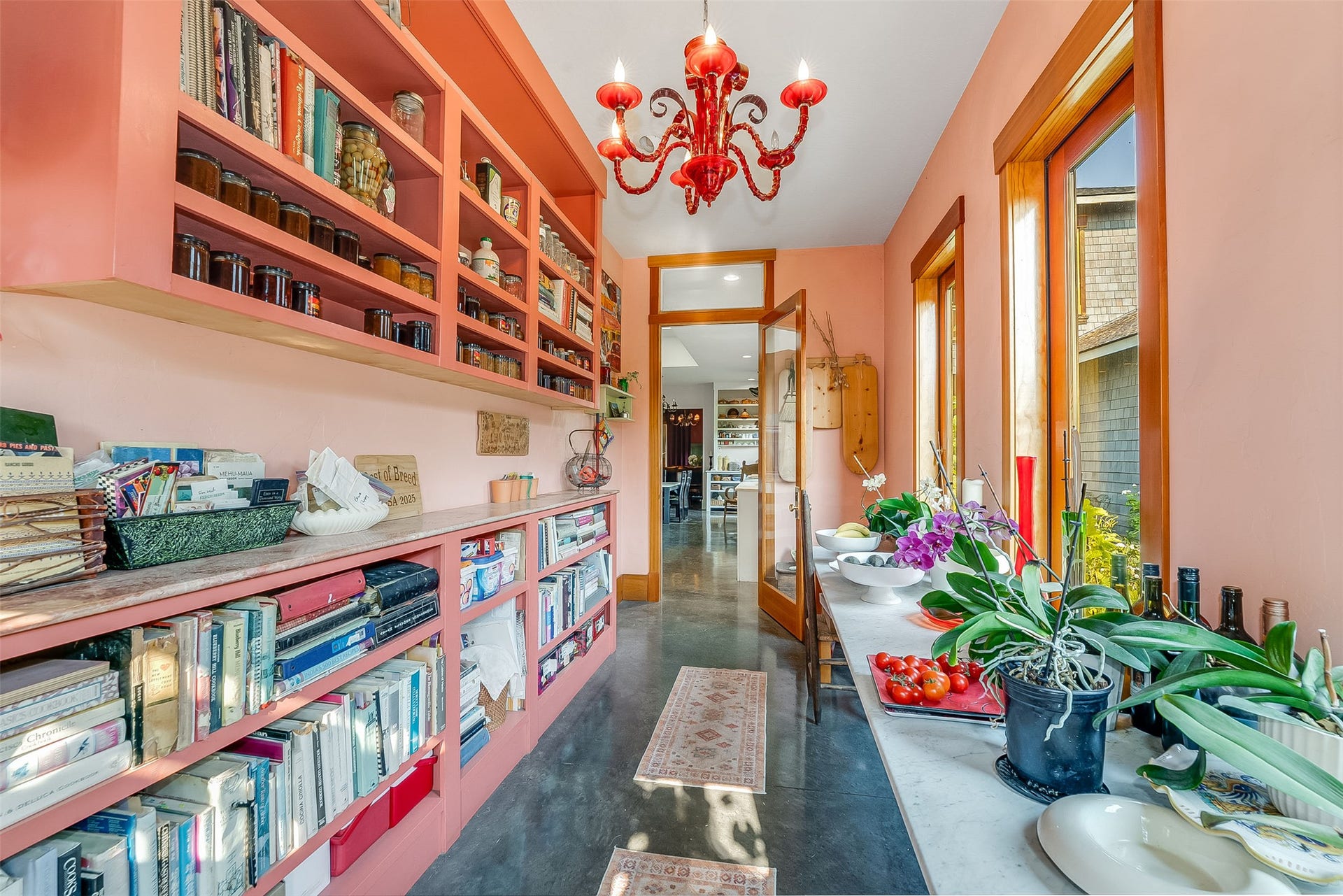 21848 Mt Highway 35, Bigfork, MT 59911 Receiving area and sunroom/hallway to kitchen. Floor to ceiling shelving for display of fruit preserves and glassware. Windows look out to central courtlyard.
