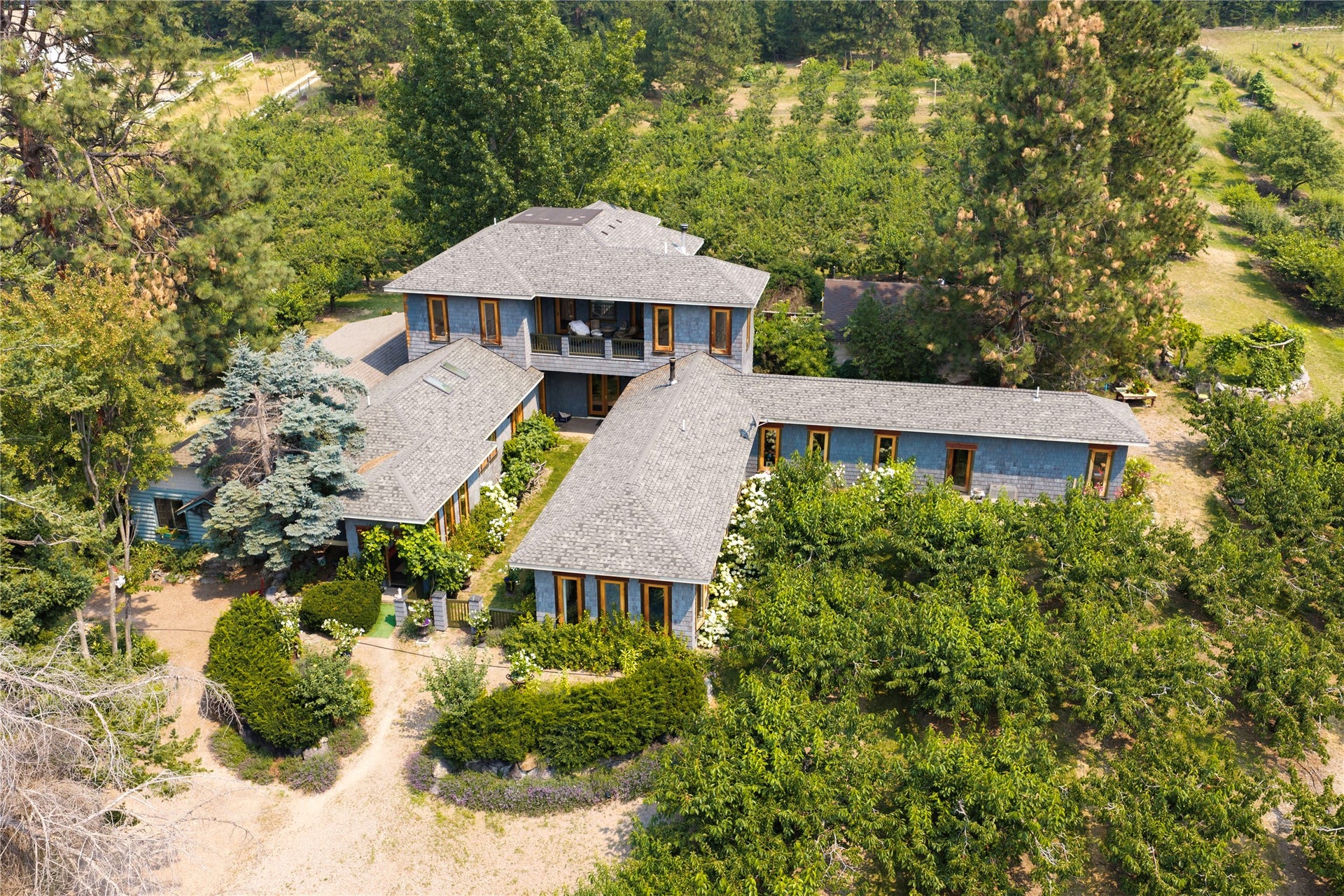 21848 Mt Highway 35, Bigfork, MT 59911 Sprawling property featuring a multi-wing residence with orchard, mature landscaping, and second-story balcony