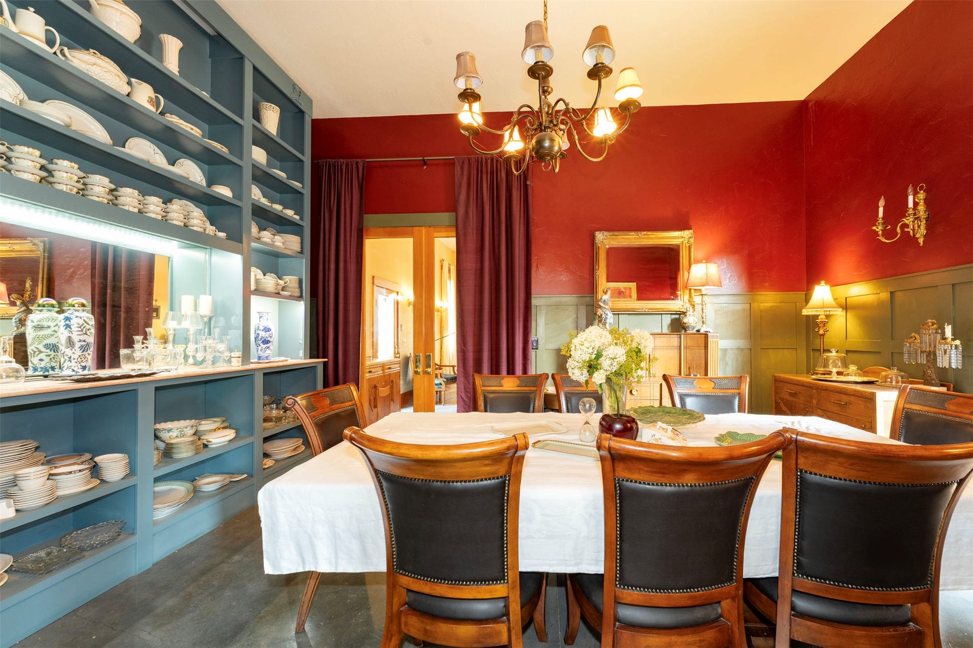 21848 Mt Highway 35, Bigfork, MT 59911 Formal dining room featuring a long rectangular table with eight chairs, a large built-in shelving unit, red wall paint, and green wainscoting