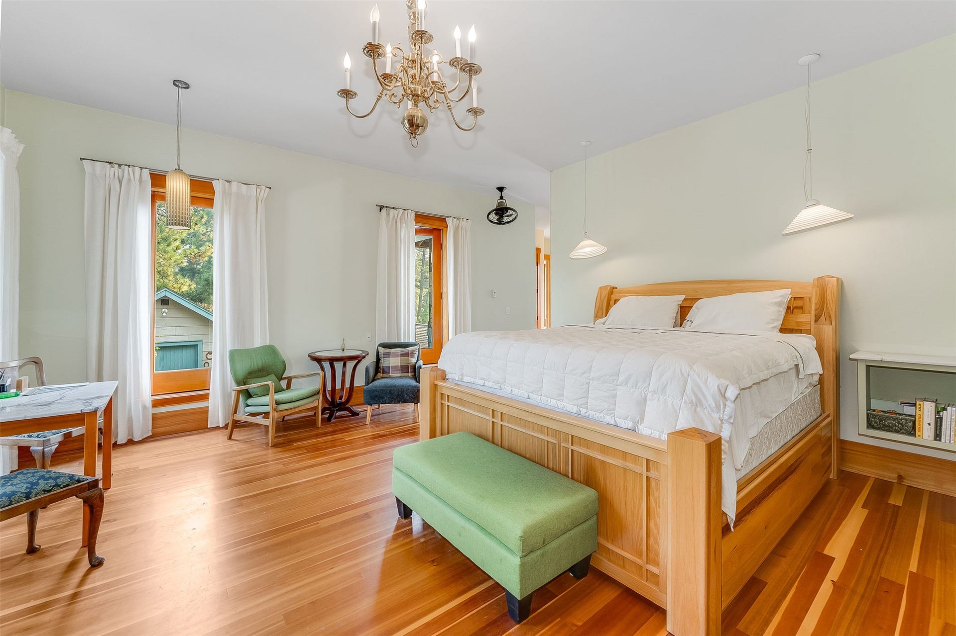 21848 Mt Highway 35, Bigfork, MT 59911 Spacious room featuring wood-finish flooring, a brass chandelier, two sets of French doors, and a built-in shelving unit