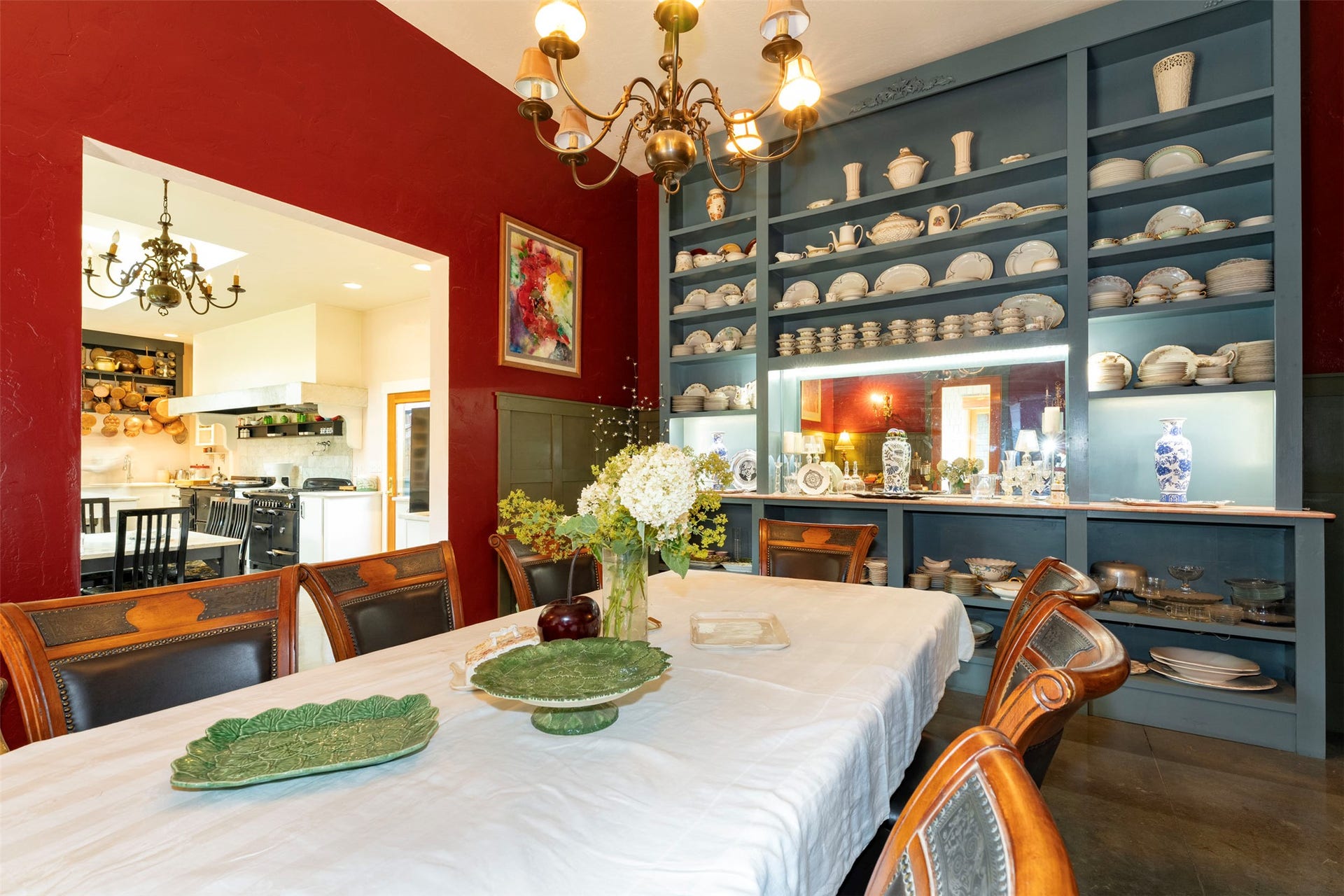 21848 Mt Highway 35, Bigfork, MT 59911 Dining area featuring a built-in display cabinet with integrated lighting, richly colored walls, an ornate chandelier, and an open pass-through to the kitchen