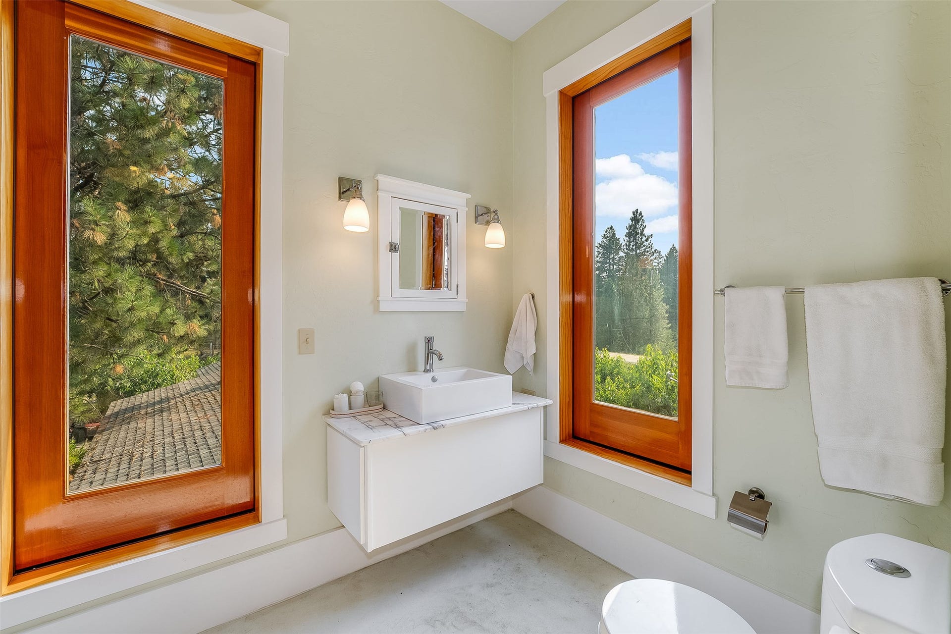 21848 Mt Highway 35, Bigfork, MT 59911 Contemporary bathroom featuring a floating vanity with a square vessel sink, a mirrored medicine cabinet, and sconce lighting