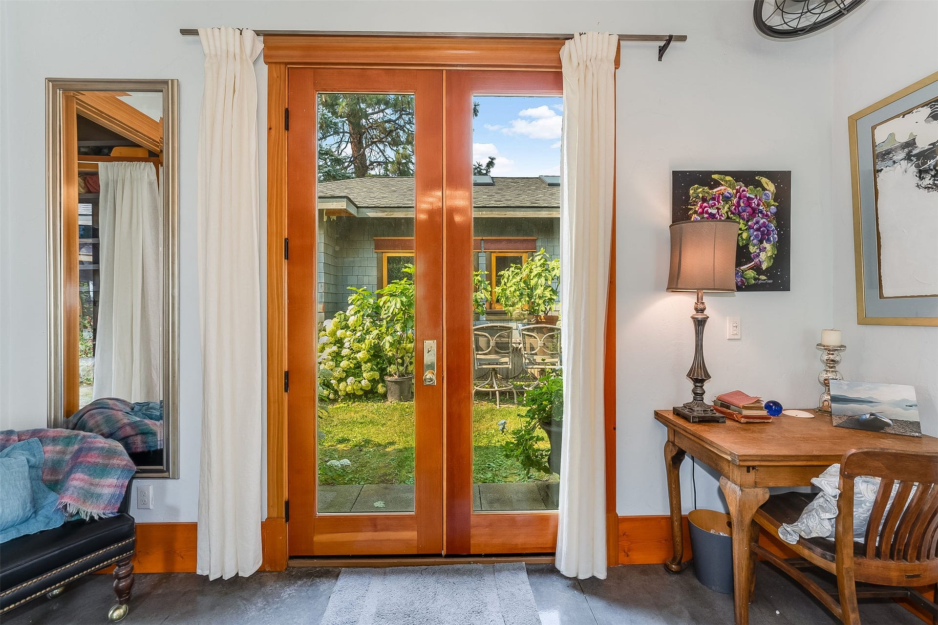 21848 Mt Highway 35, Bigfork, MT 59911 Wood-finish French living room entry doors with glass panels open to courtyard featuring mature landscaping
