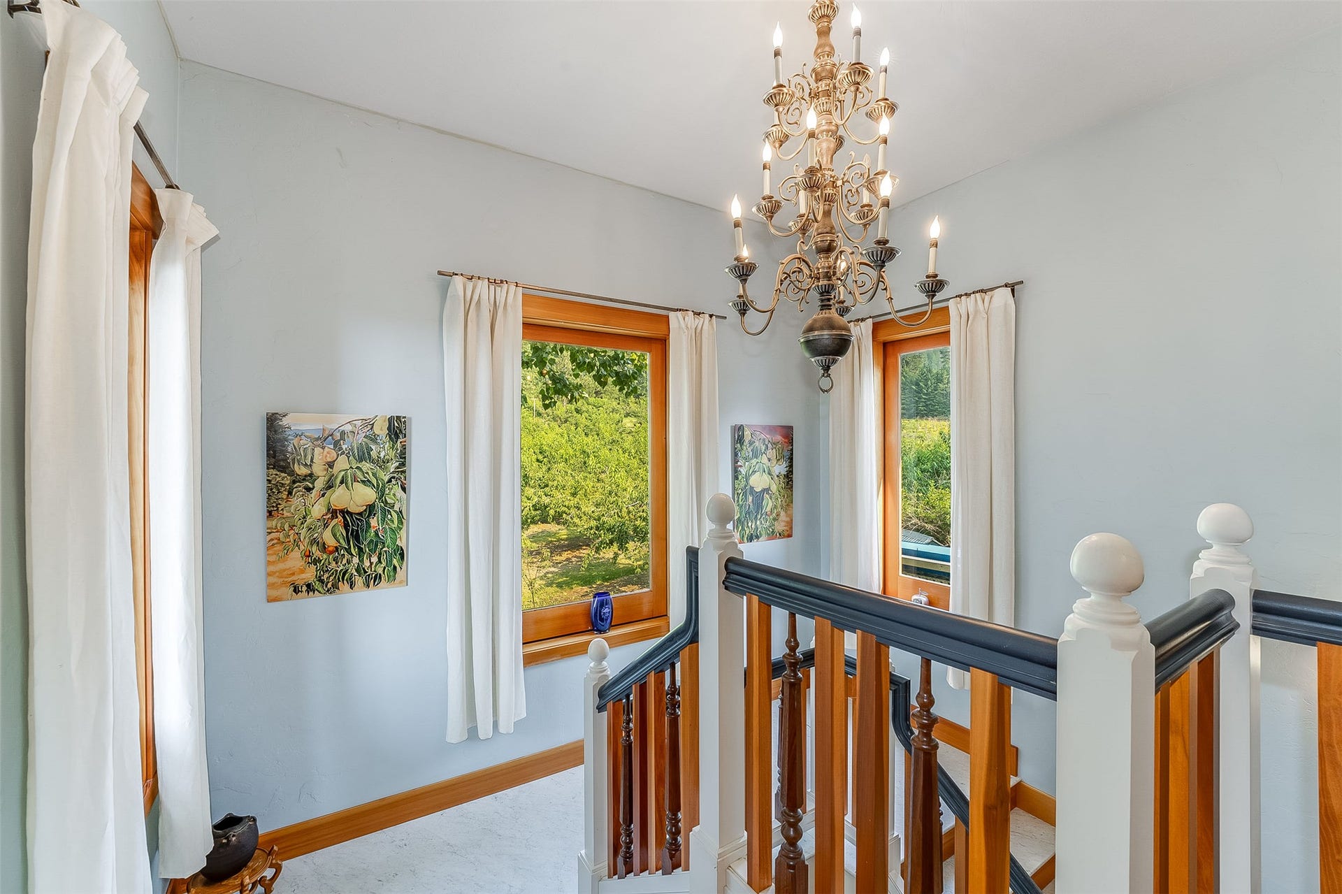 21848 Mt Highway 35, Bigfork, MT 59911 Landing on Staircase to Primary Bedrooms featuring wood balusters with painted rails, a wood-frame window, and a chandelier lighting fixture