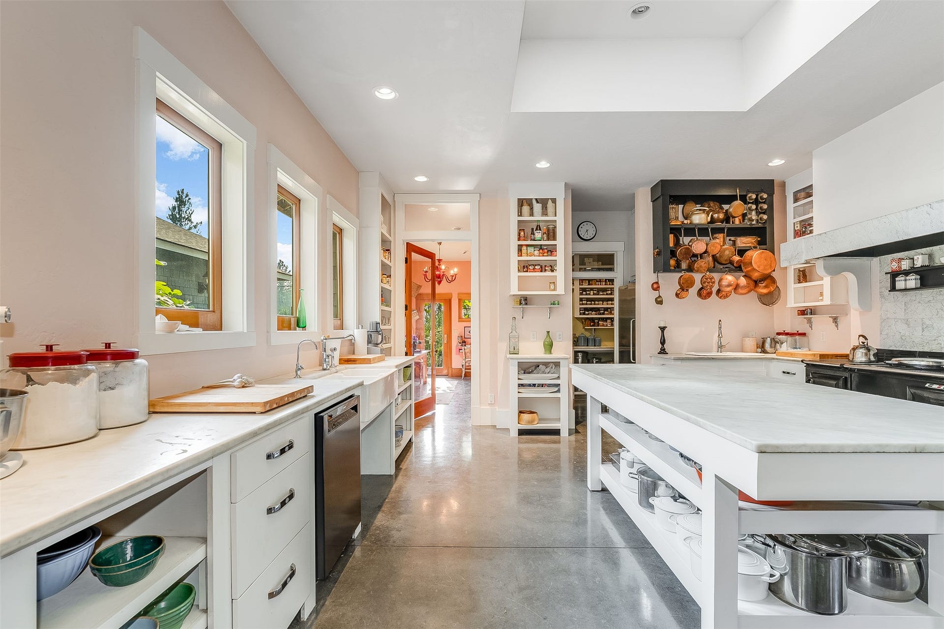 21848 Mt Highway 35, Bigfork, MT 59911 Expansive kitchen featuring a large central island with open shelving, a prominent range hood, and multiple windows providing natural light