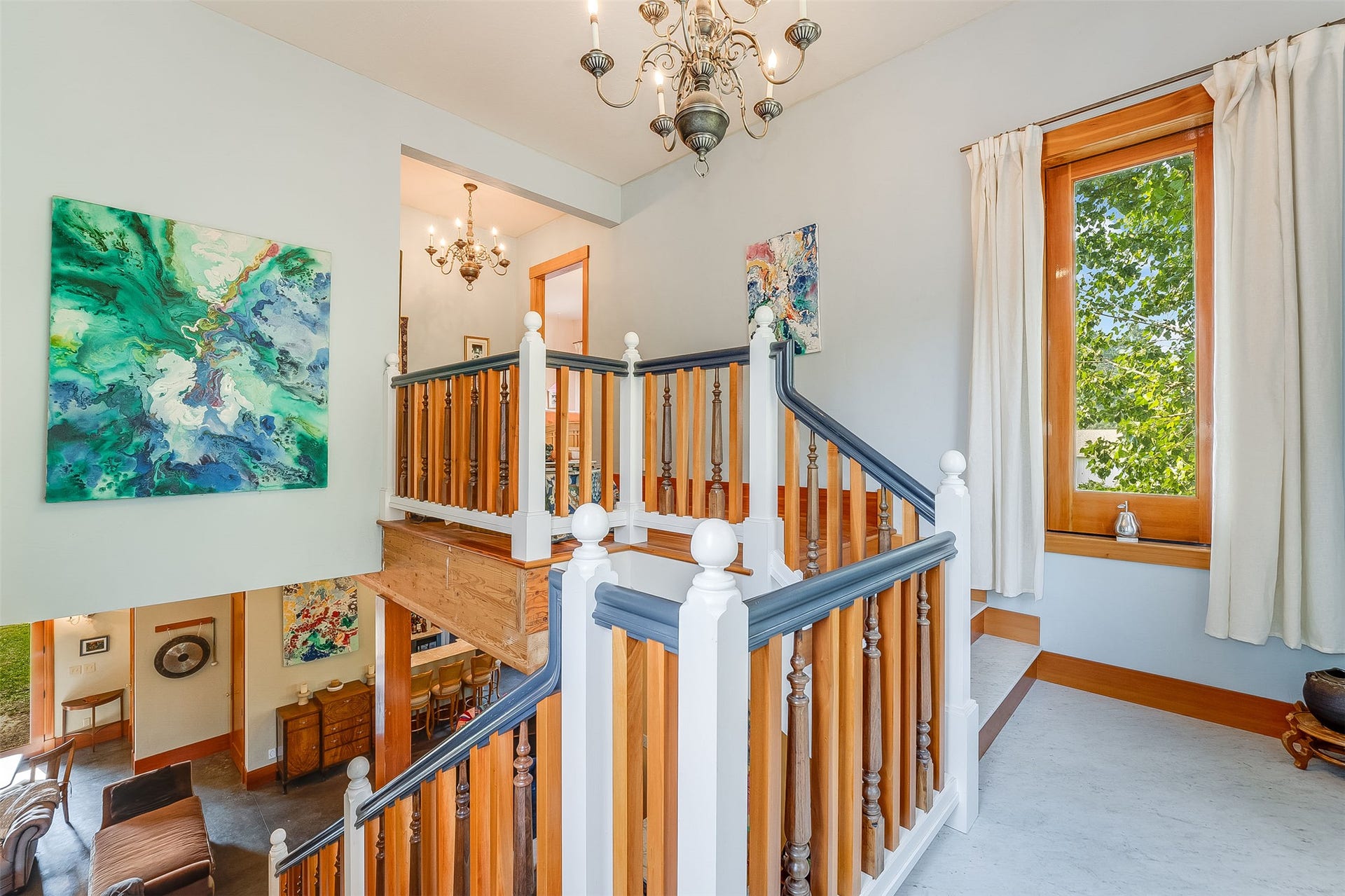 21848 Mt Highway 35, Bigfork, MT 59911 Landing on Staircase featuring wood balusters with painted rails, a wood-frame window, and a chandelier lighting fixture