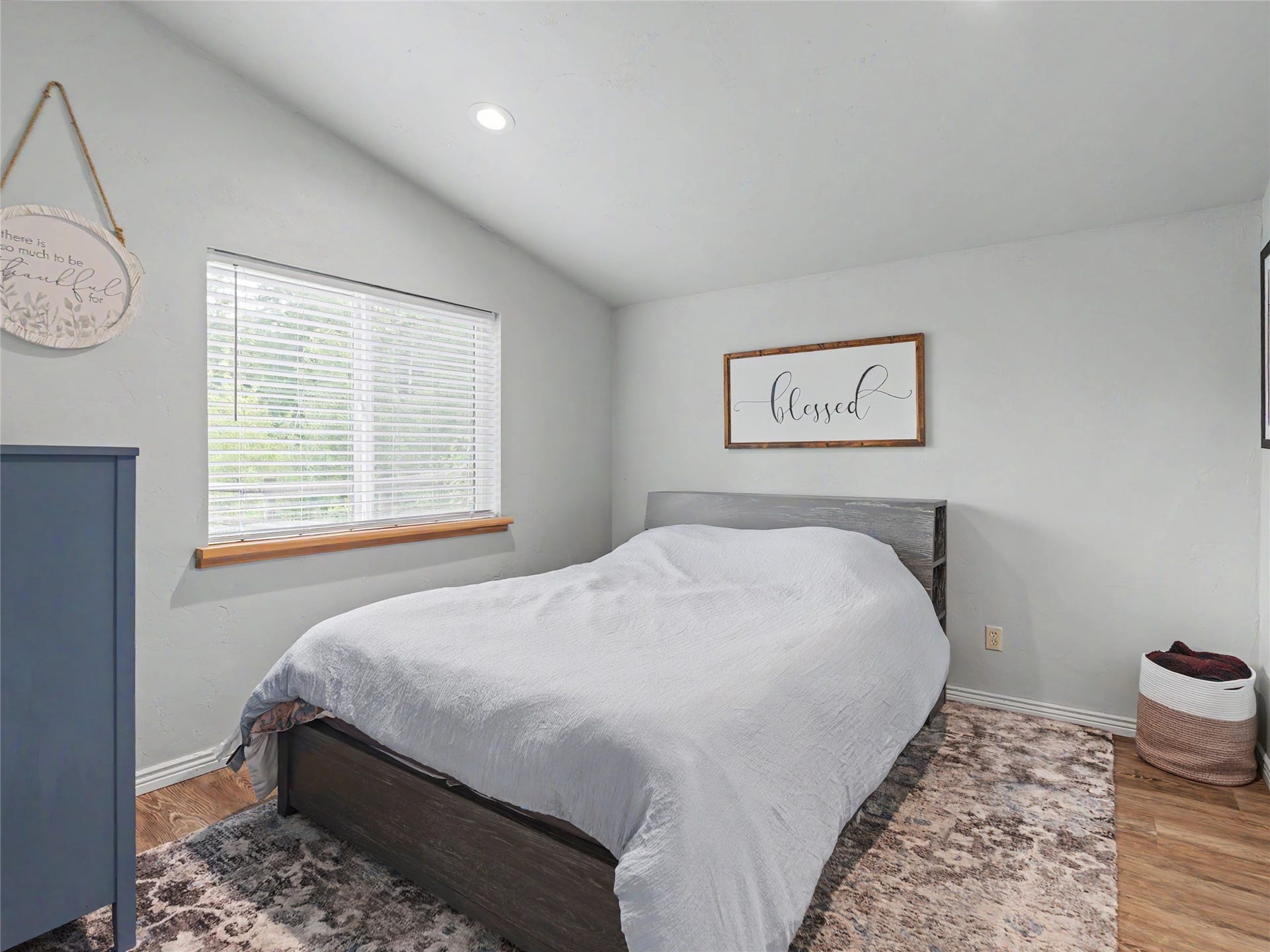 28012 Meadow Creek Road, Bigfork, MT 59911 Guest quarters bedroom with sloped ceiling room featuring a window with wood trim, wood-finish flooring, and recessed lighting