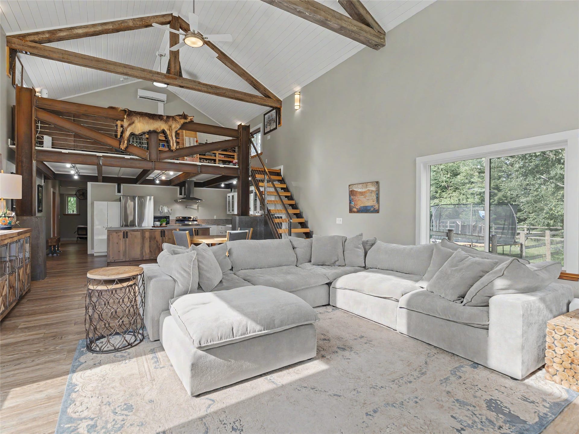 28012 Meadow Creek Road, Bigfork, MT 59911 Vaulted ceiling with exposed wood beams, wood-finish flooring, sliding glass door, loft area with wood staircase, and stainless steel kitchen appliances