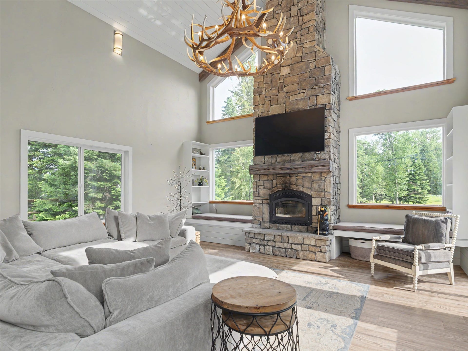 28012 Meadow Creek Road, Bigfork, MT 59911 Vaulted living area featuring a stone fireplace with hearth, a wood mantel, and integrated media space