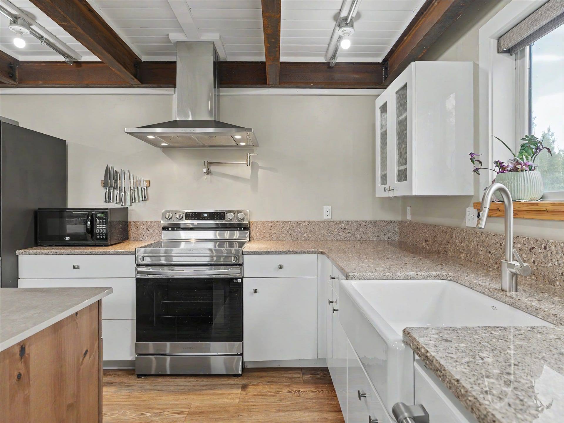 28012 Meadow Creek Road, Bigfork, MT 59911 Kitchen featuring wood-finish flooring, white cabinetry, and stone countertops