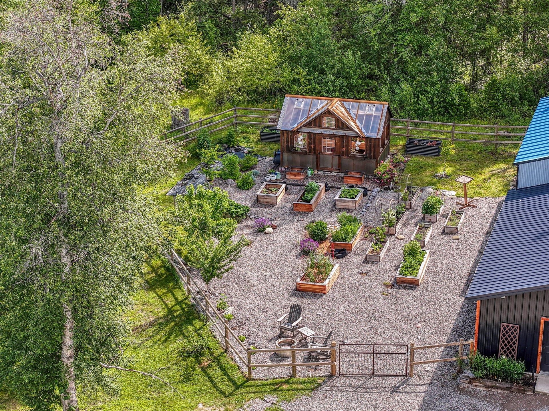 28012 Meadow Creek Road, Bigfork, MT 59911 Expansive garden area featuring a wood-framed greenhouse with a clear panel roof, numerous raised garden beds, gravel pathways, and a wooden fence boundary