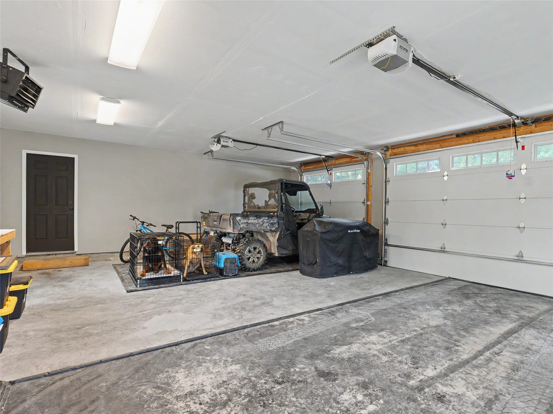 28012 Meadow Creek Road, Bigfork, MT 59911 Three-car garage featuring a concrete floor, overhead fluorescent lighting, and two automatic garage doors with upper window panels
