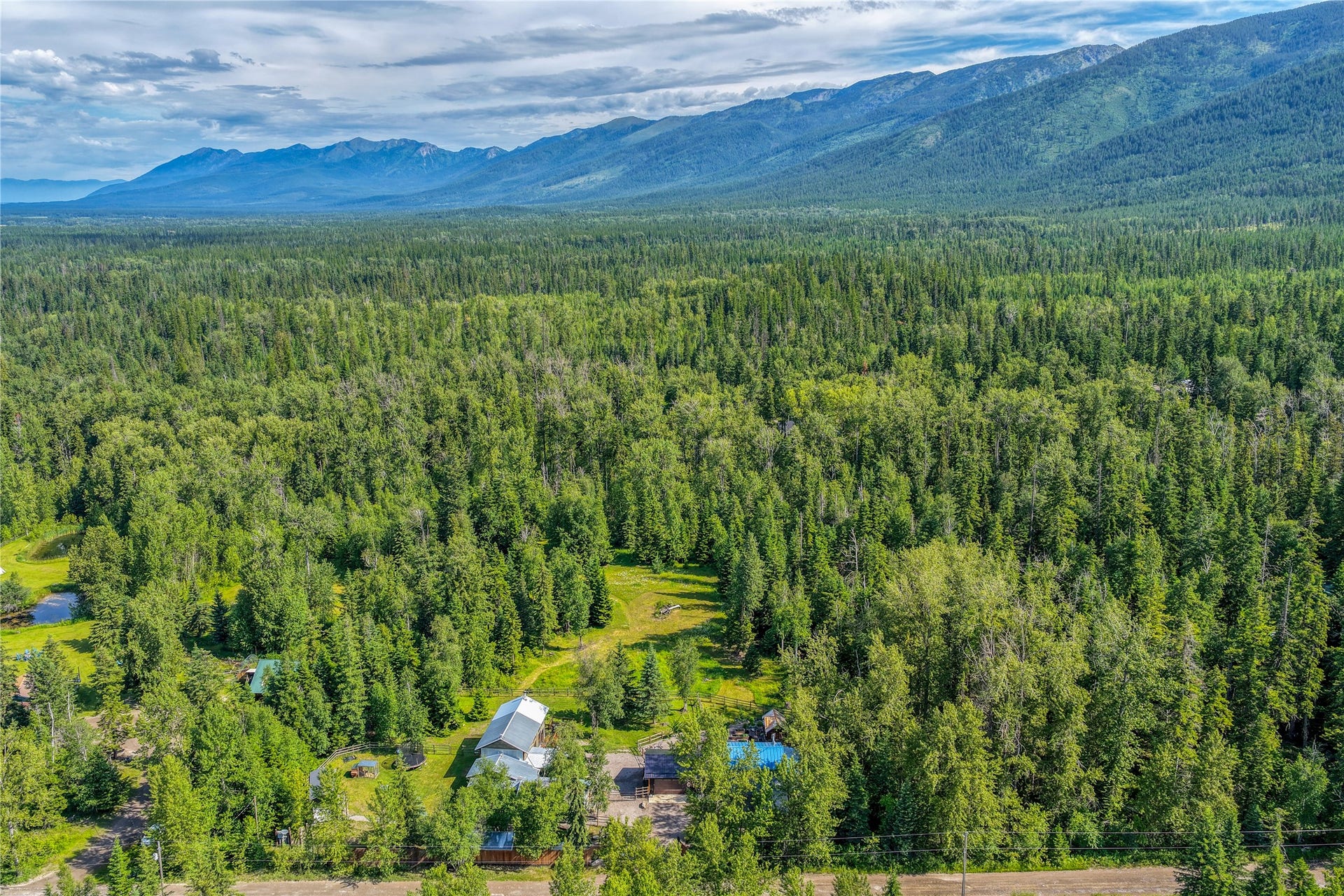 28012 Meadow Creek Road, Bigfork, MT 59911 Expansive forested landscape with a visible property featuring multiple structures and a clear clearing