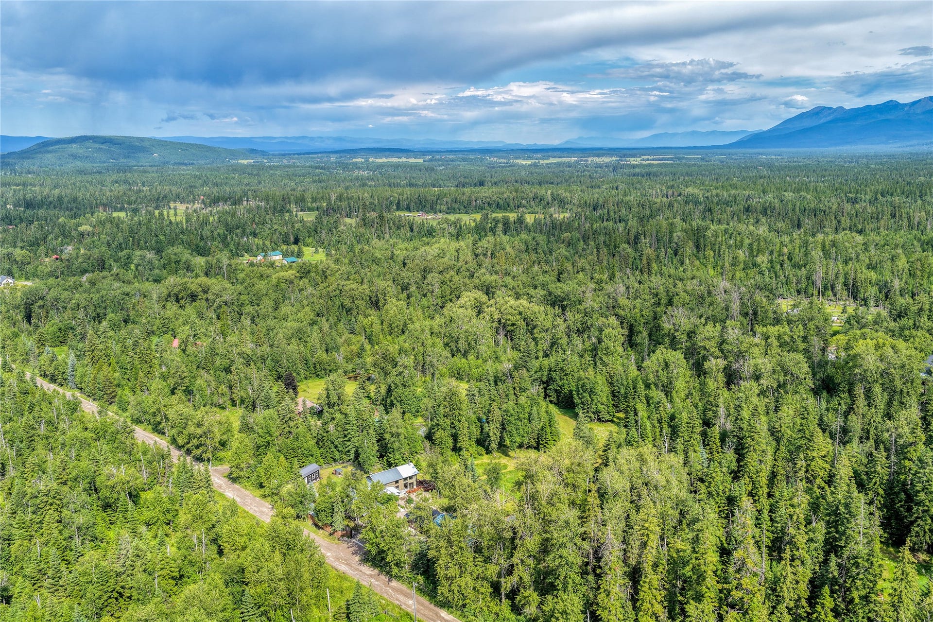 28012 Meadow Creek Road, Bigfork, MT 59911 Expansive forested landscape with distant mountain ranges and scattered residential structures