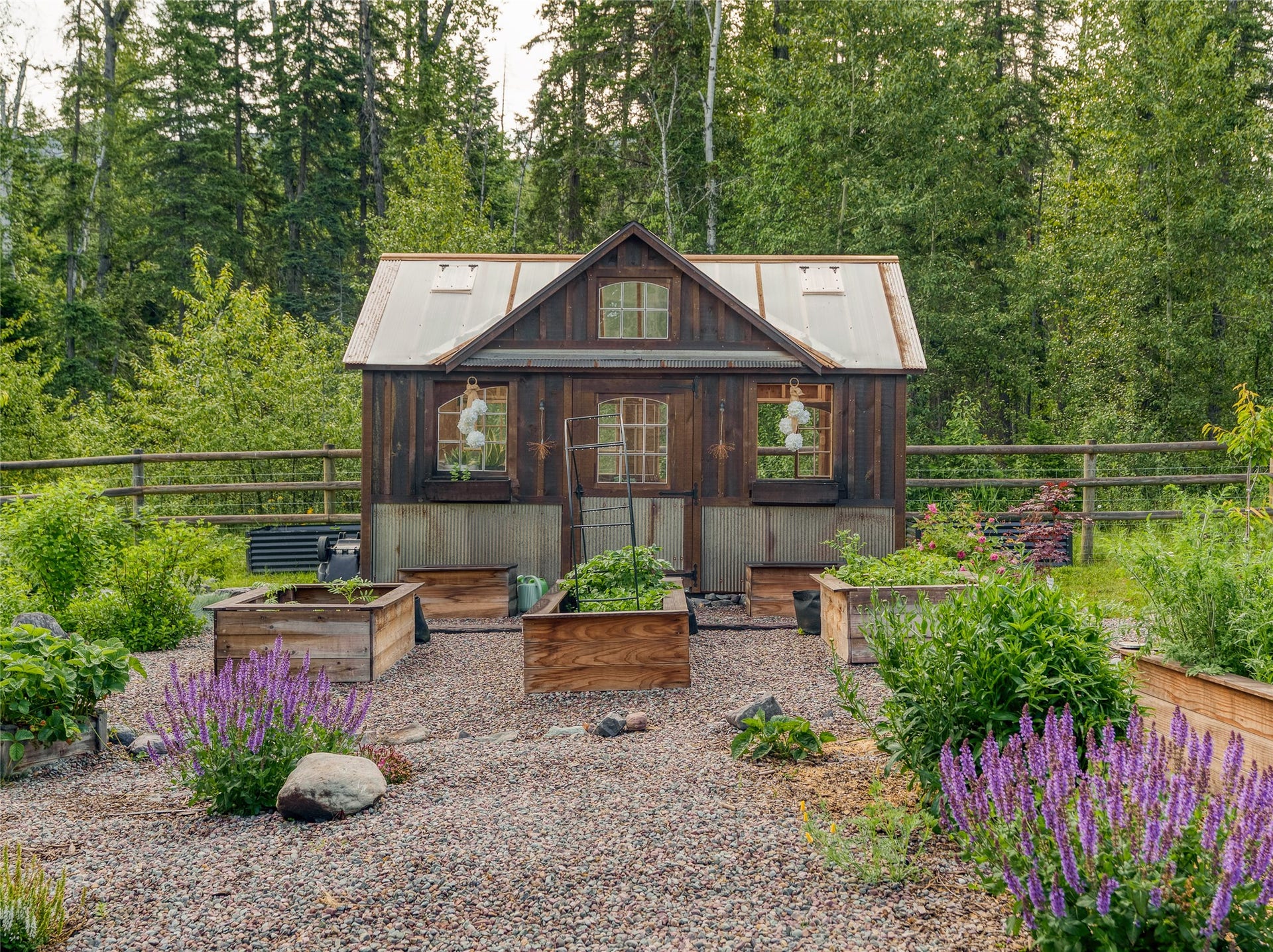28012 Meadow Creek Road, Bigfork, MT 59911 Rustic green house outbuilding featuring a sloped translucent roof, wood siding, and multiple window accents