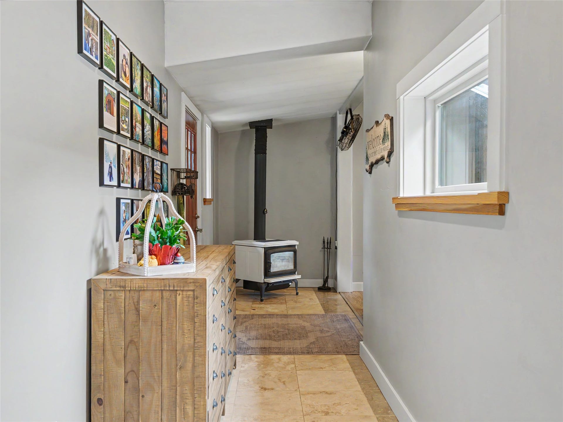 28012 Meadow Creek Road, Bigfork, MT 59911 Hallway featuring a wood-burning stove with a black flue, stone tile flooring, and light gray walls