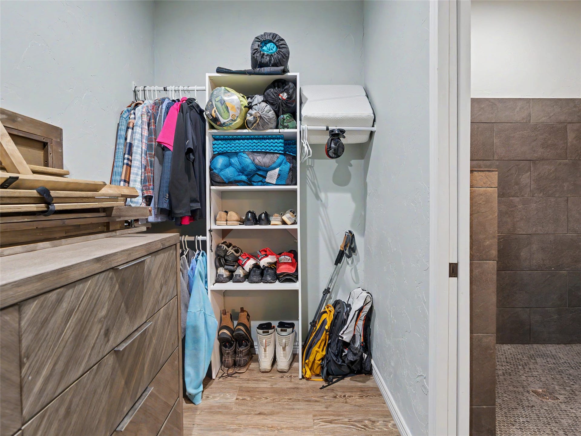 28012 Meadow Creek Road, Bigfork, MT 59911 Guest Quarters Walk-in closet featuring wood-finish flooring, built-in shelving, a clothes hanging rod, and a wood-finish dresser with contemporary hardware