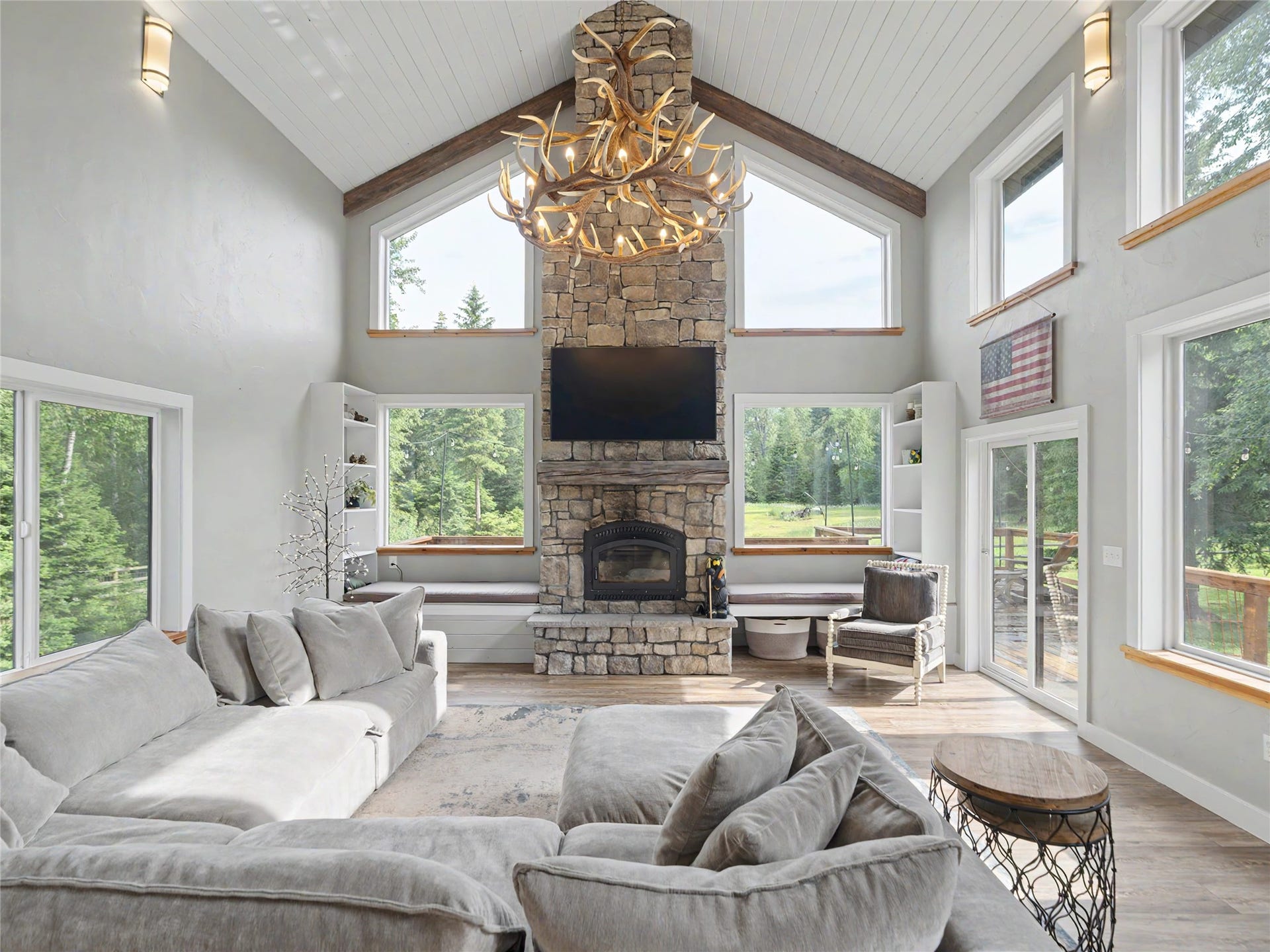 28012 Meadow Creek Road, Bigfork, MT 59911 Stone-clad fireplace extending to a vaulted ceiling with exposed wood beams and shiplap paneling
