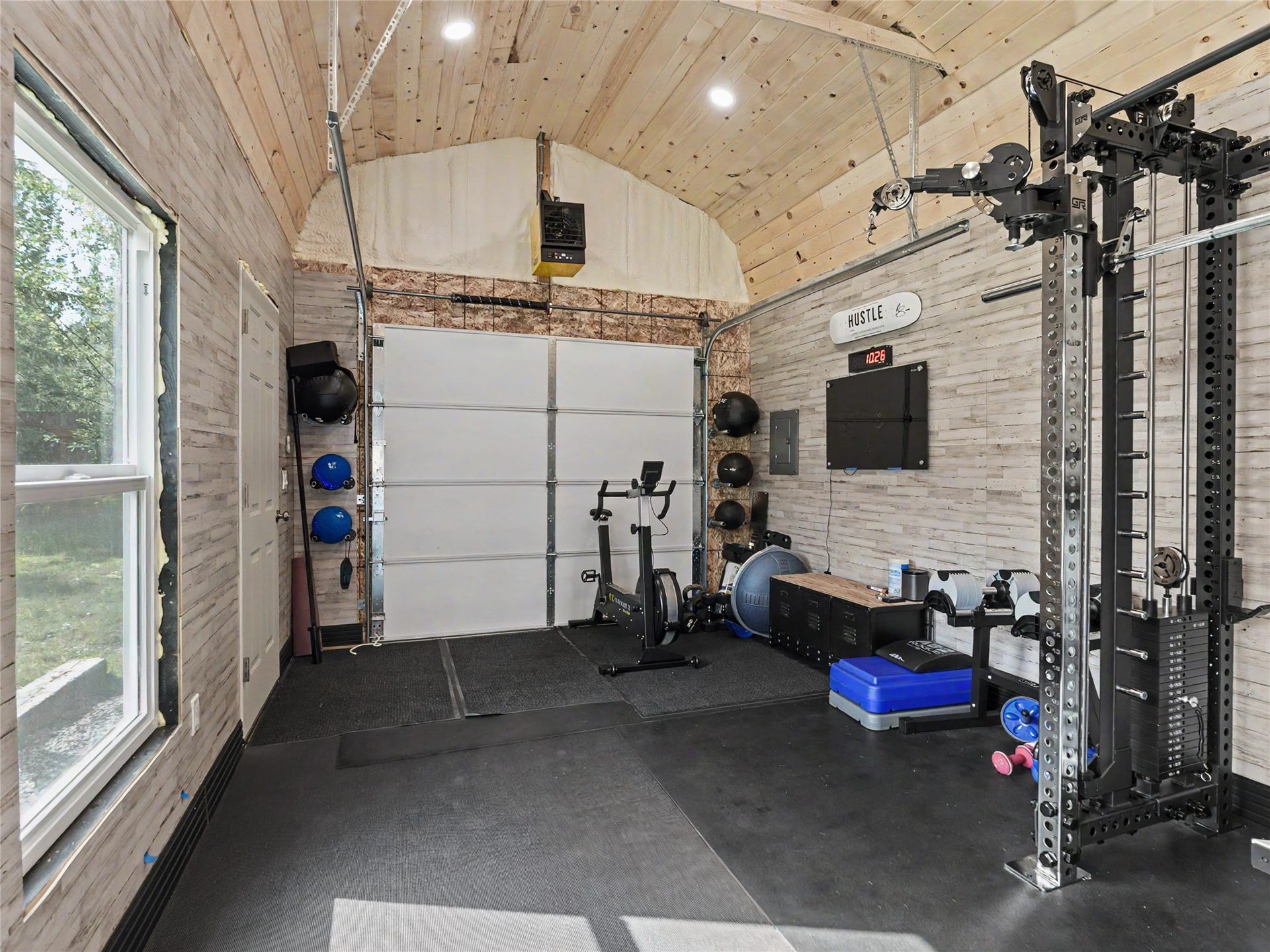 28012 Meadow Creek Road, Bigfork, MT 59911 Versatile interior space featuring wood-finish paneling, a vaulted ceiling with recessed lighting, and durable rubber flooring