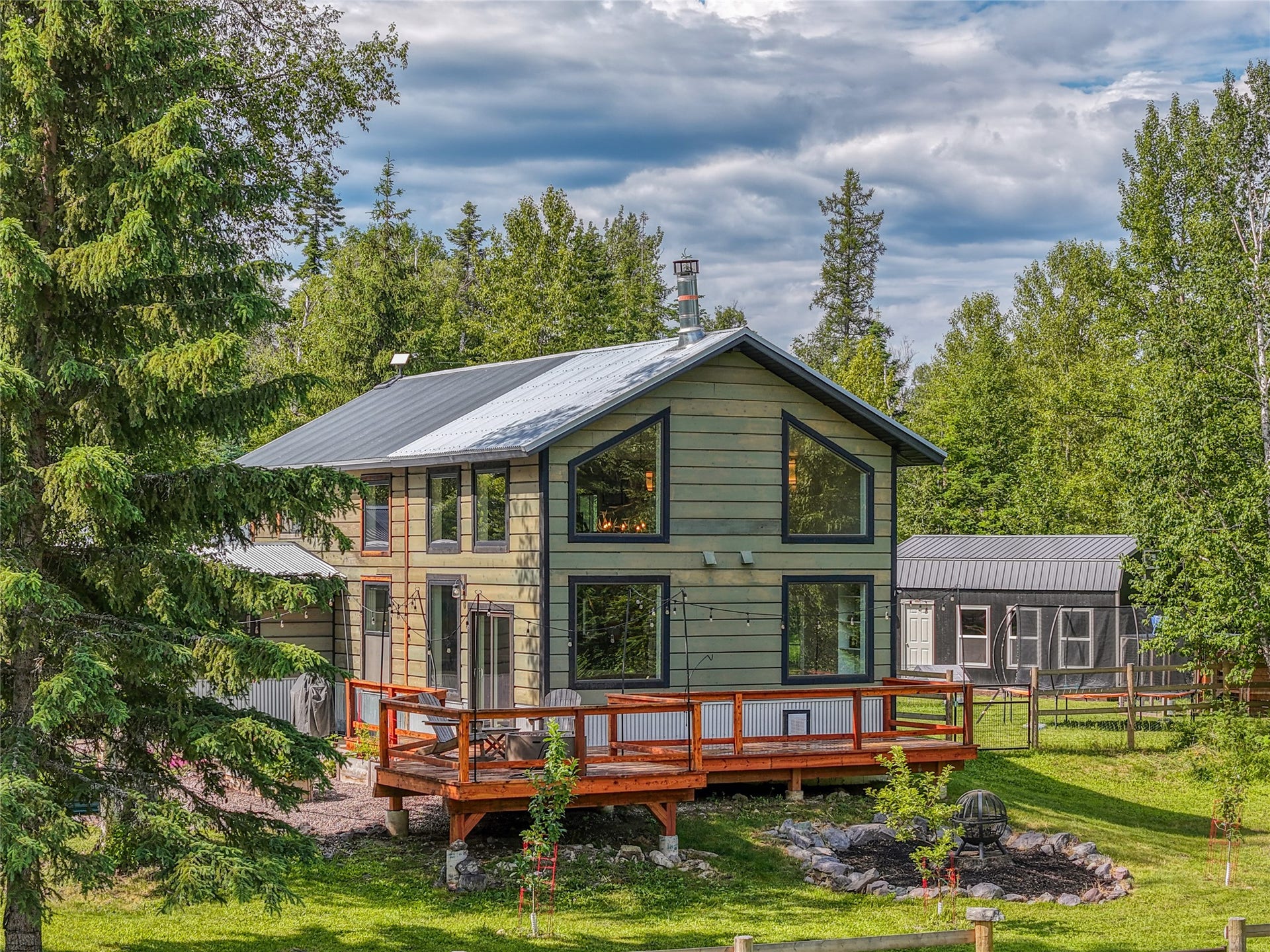 28012 Meadow Creek Road, Bigfork, MT 59911 Two-story dwelling featuring a metal roof, wood siding, and an expansive wood deck