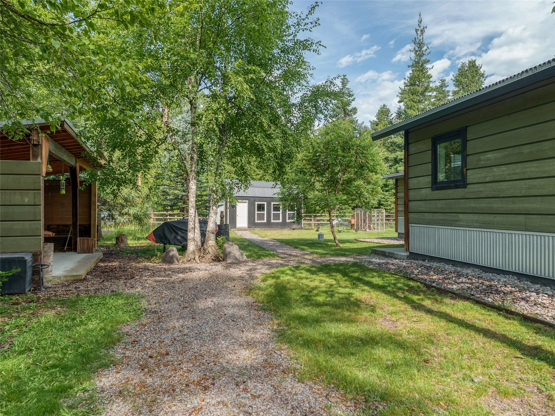 28012 Meadow Creek Road, Bigfork, MT 59911 Property exterior featuring green horizontal siding, a corrugated metal foundation skirt, and a dark-framed window