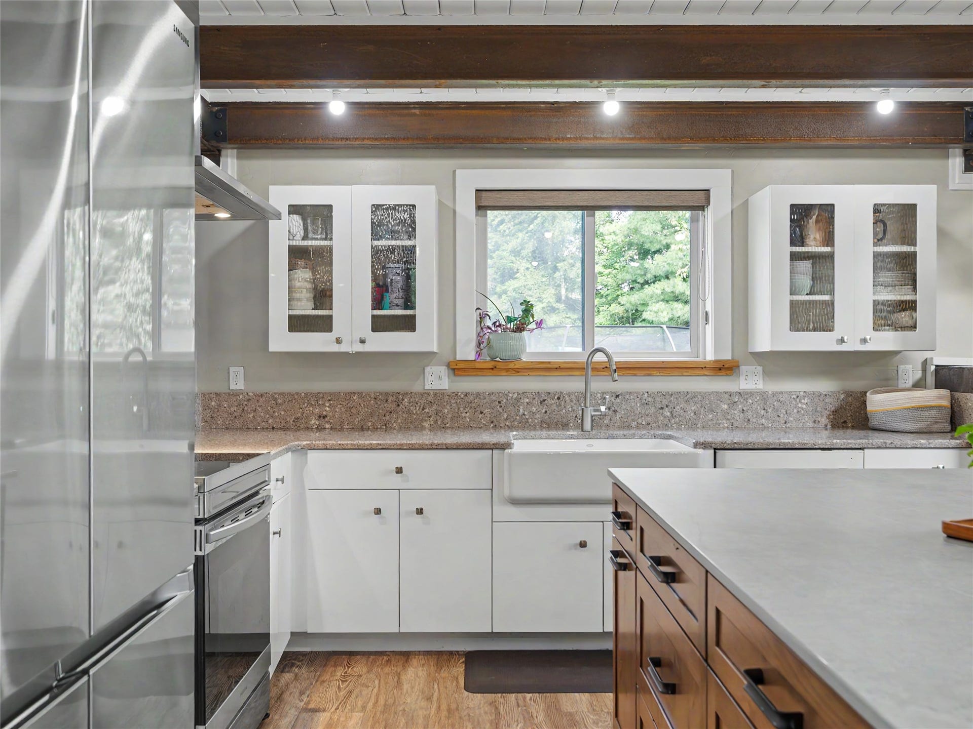 28012 Meadow Creek Road, Bigfork, MT 59911 Modern kitchen featuring white shaker cabinetry, stainless steel appliances, a farmhouse sink, and wood-finish flooring