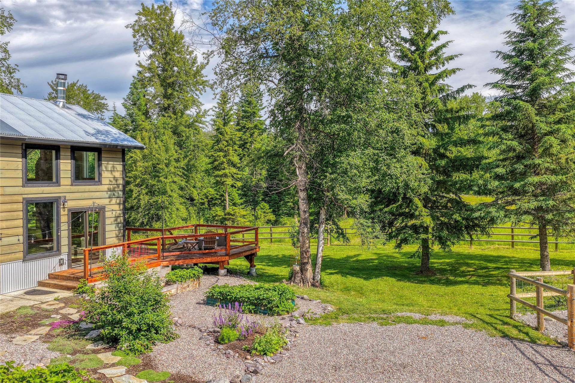 28012 Meadow Creek Road, Bigfork, MT 59911 Exterior featuring wood siding, a metal roof, and a wood deck with railings