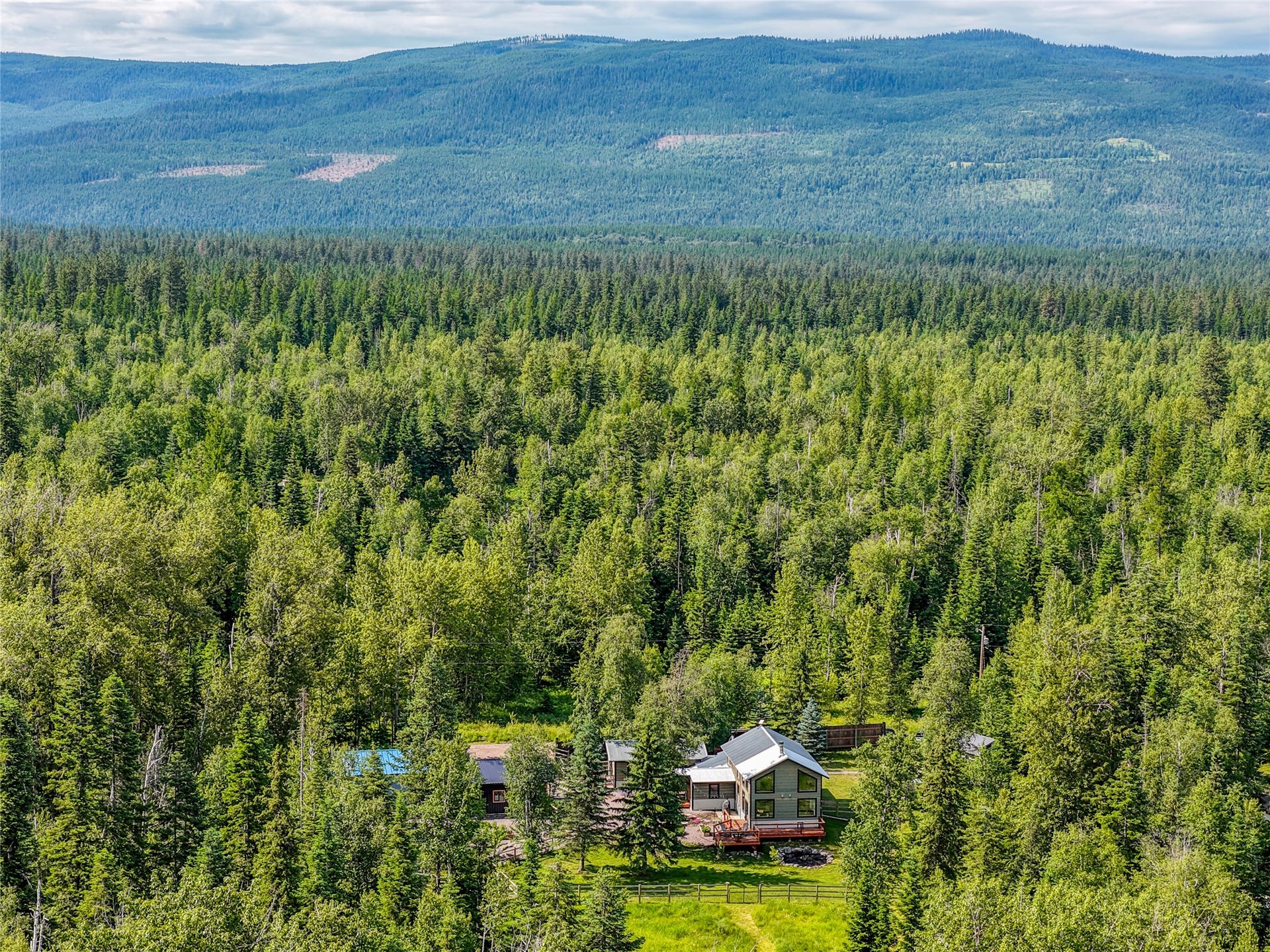28012 Meadow Creek Road, Bigfork, MT 59911 Wooded landscape featuring a residential structure with a light-colored roof and an expansive surrounding forest