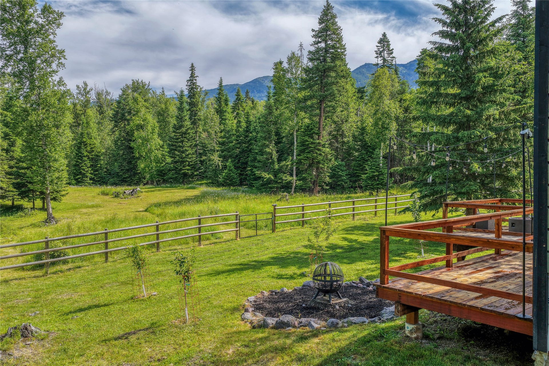 28012 Meadow Creek Road, Bigfork, MT 59911 Expansive green lawn framed by a rustic wooden fence and mature trees
