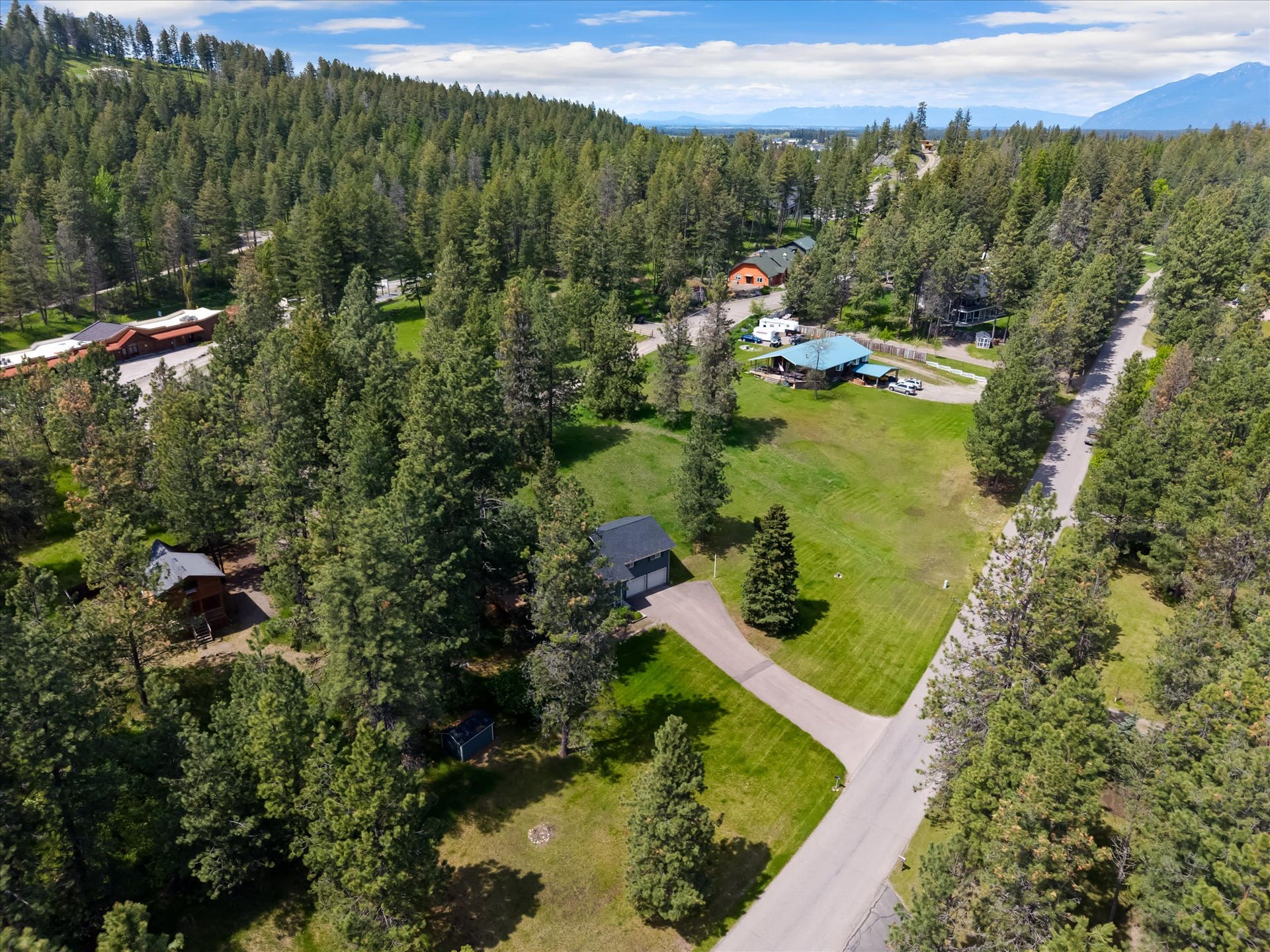 300 Peaceful Drive, Bigfork, MT 59911 Expansive property featuring a paved driveway, a two-car attached garage, and a lush green lawn