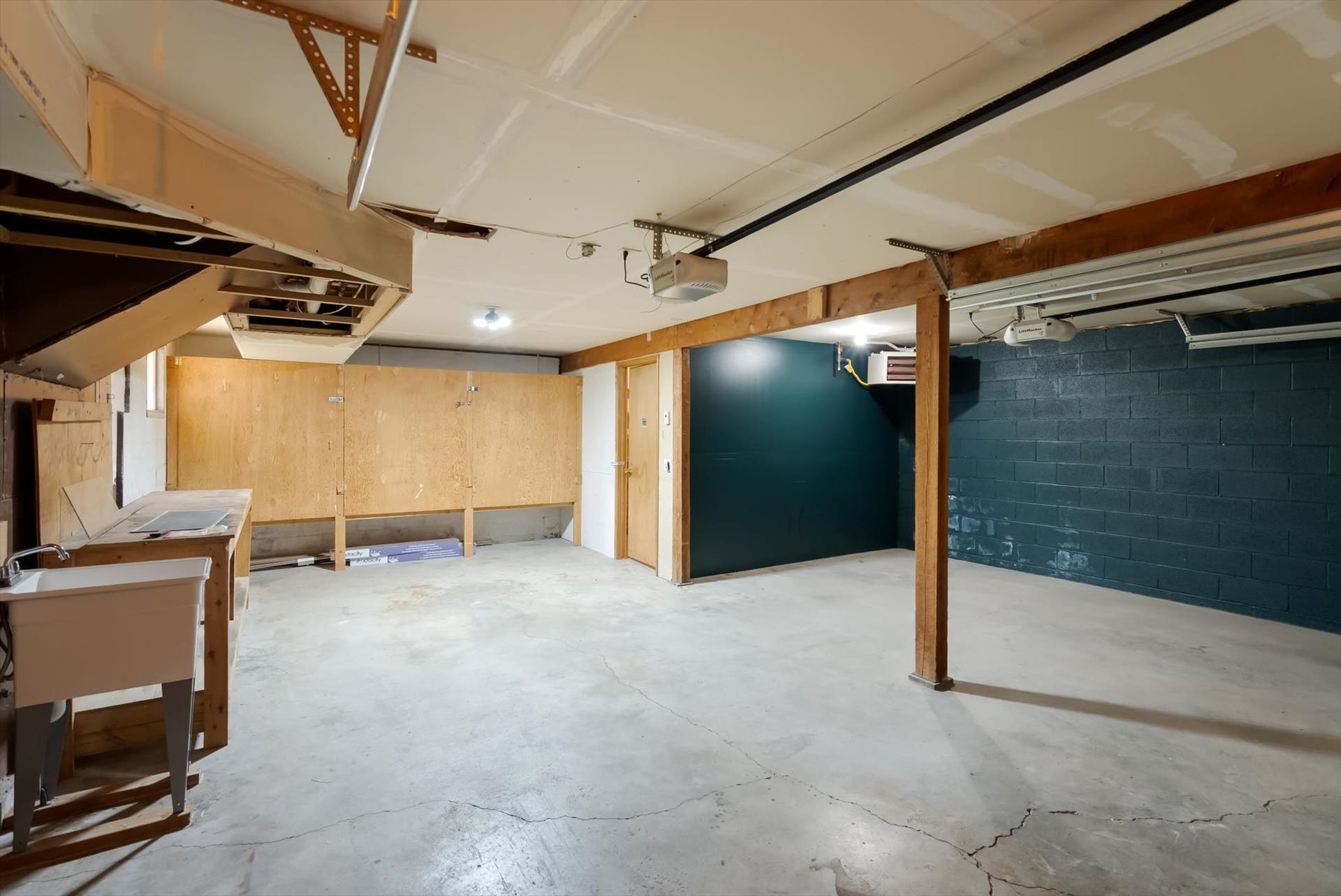 300 Peaceful Drive, Bigfork, MT 59911 Utility room featuring a concrete floor, exposed ceiling joists, a utility sink, and painted cinder block walls