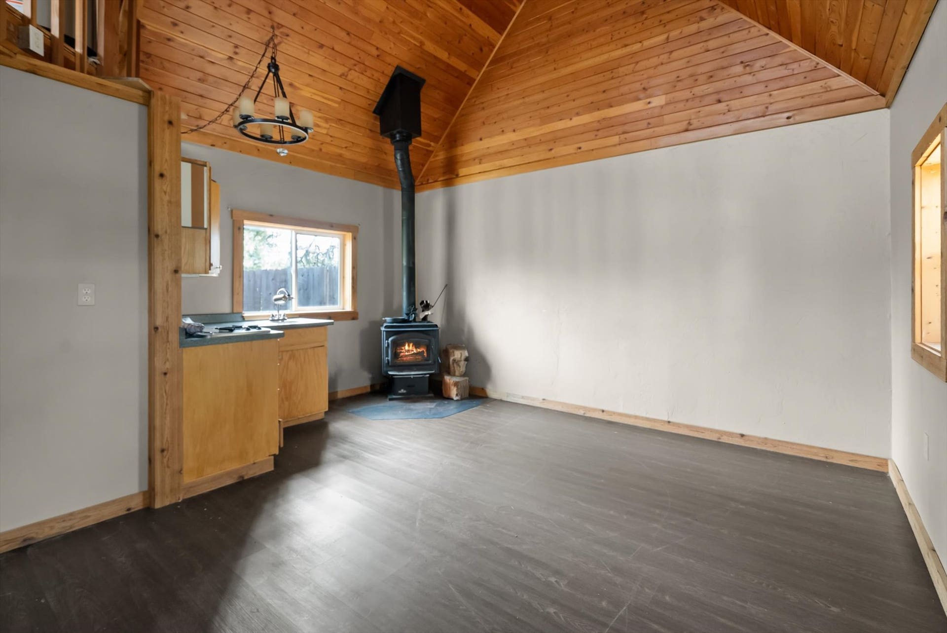 300 Peaceful Drive, Bigfork, MT 59911 Open-concept interior featuring a vaulted wood-finish ceiling, wood-burning stove, and dark wood-finish flooring