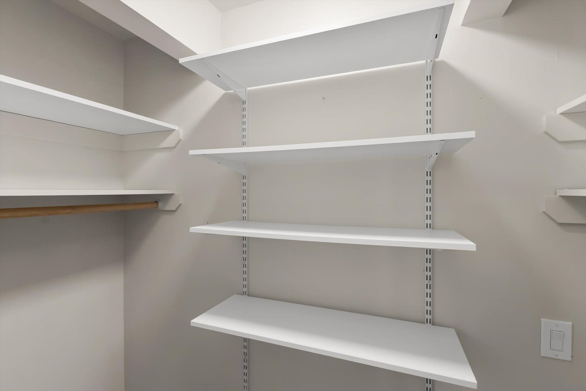 300 Peaceful Drive, Bigfork, MT 59911 Closet system featuring multiple white adjustable shelves and a wooden clothing rod