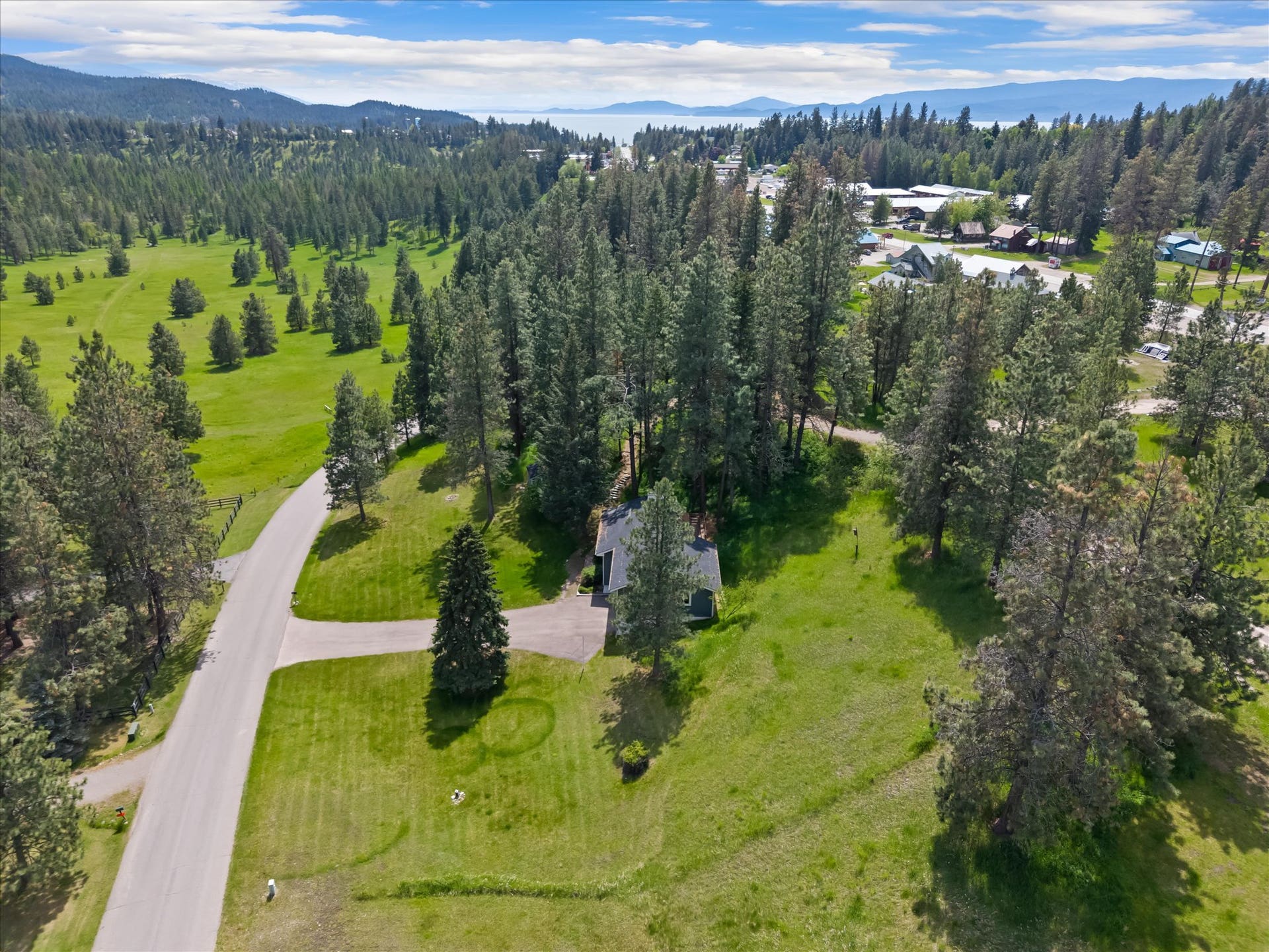 300 Peaceful Drive, Bigfork, MT 59911 Expansive property featuring a single-story residence, mature evergreen trees, manicured lawns, and a paved driveway