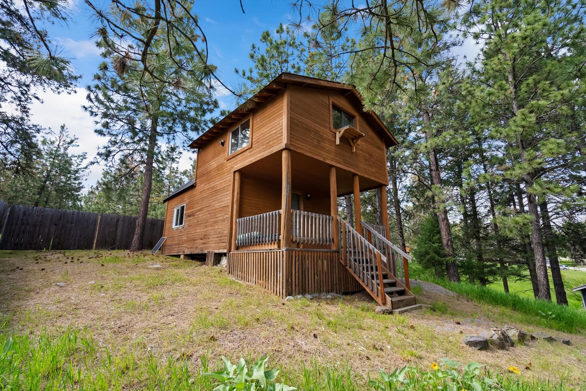 300 Peaceful Drive, Bigfork, MT 59911 Two-story wood-sided cabin featuring a covered front porch with railings, exterior staircase, and multiple windows