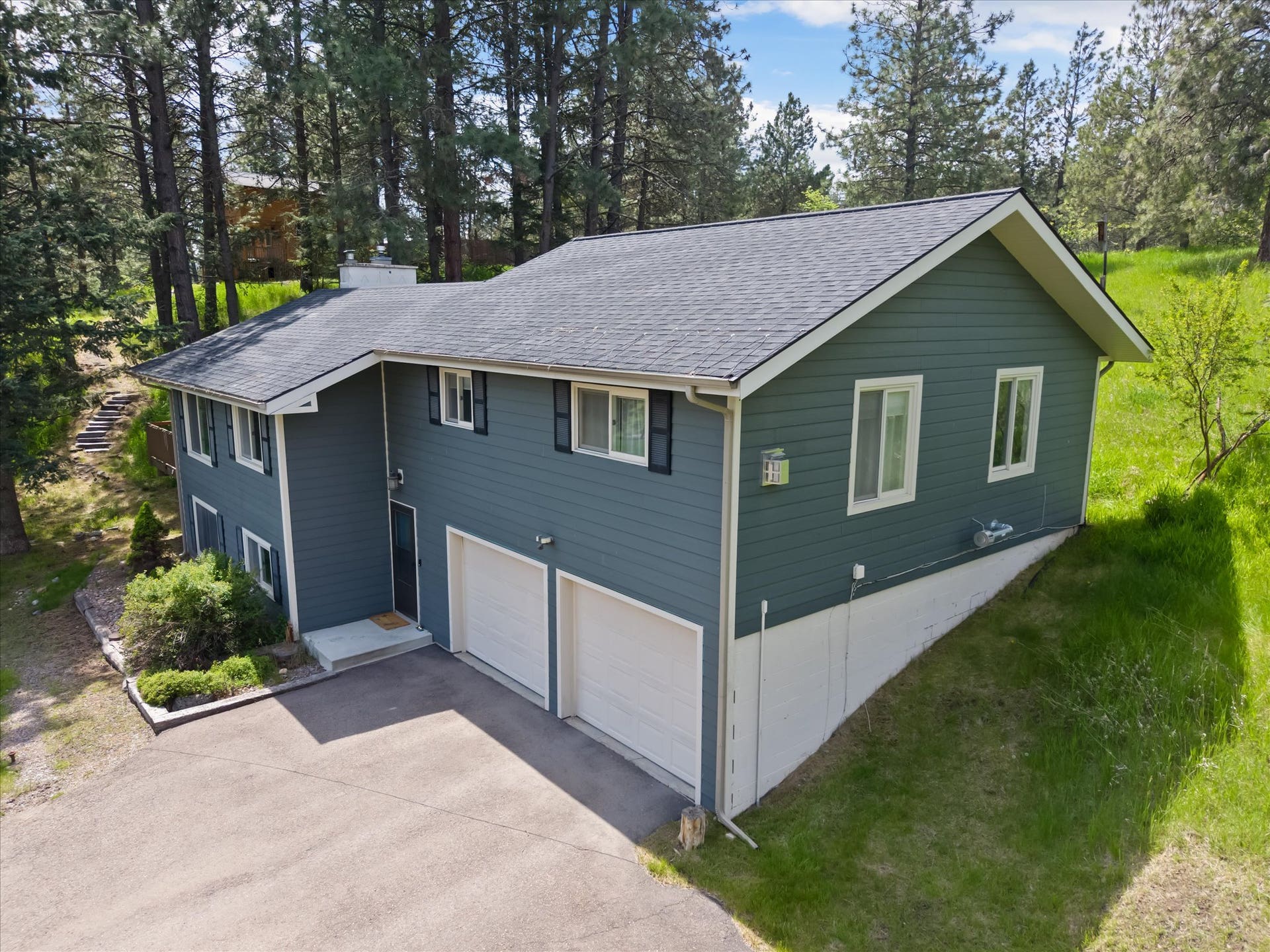 300 Peaceful Drive, Bigfork, MT 59911 Multi-level residence featuring a gray asphalt shingle roof, blue siding, and white trim