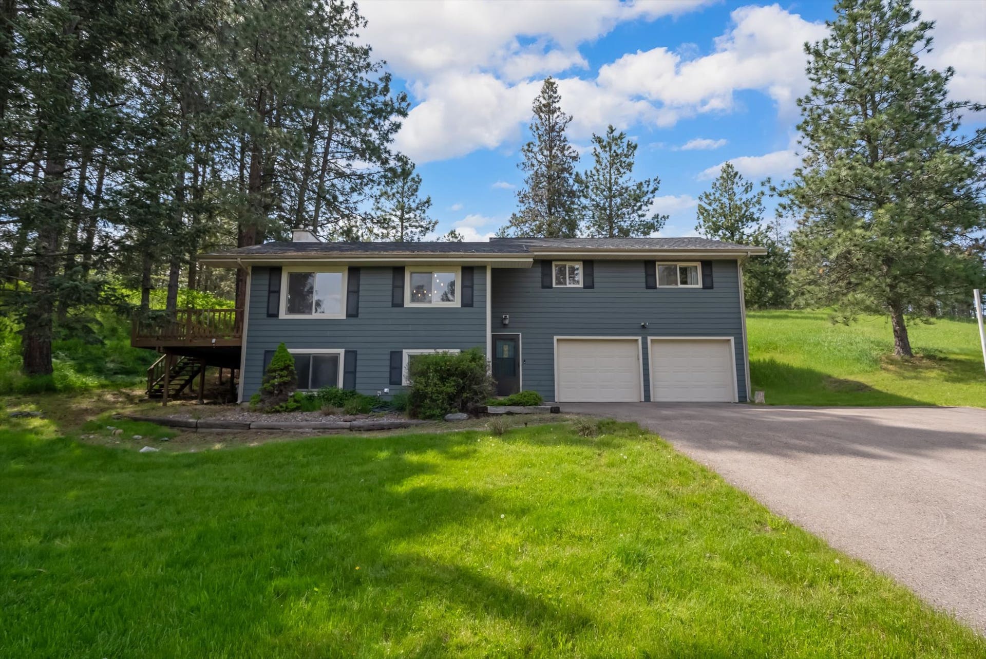 300 Peaceful Drive, Bigfork, MT 59911 Split-level residence featuring a gray exterior siding, a two-car garage with white doors, and a paved driveway