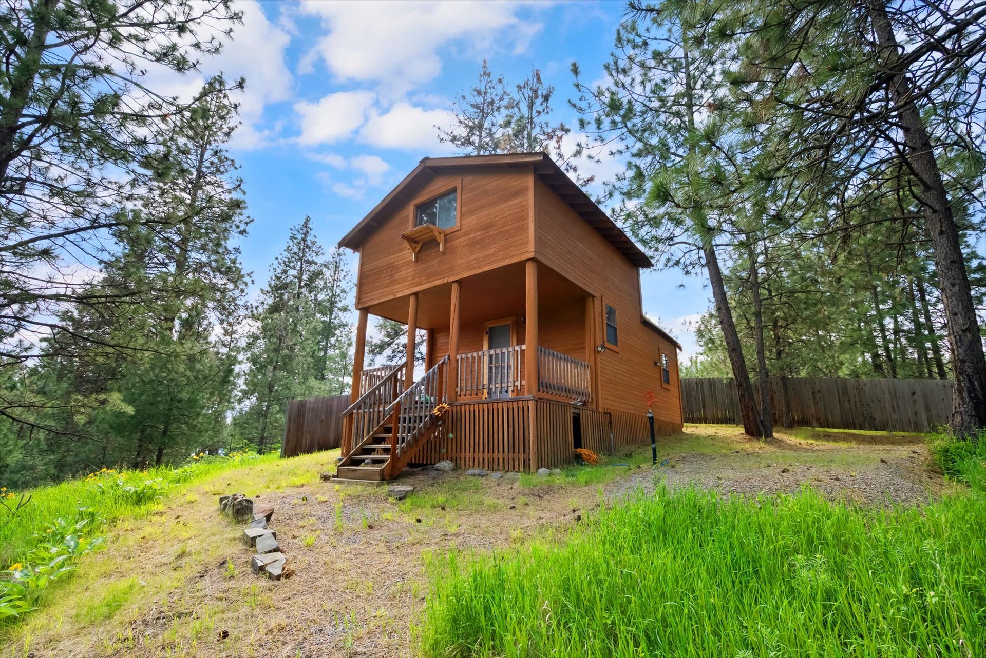 300 Peaceful Drive, Bigfork, MT 59911 Wood-sided home featuring a covered front porch with railings and a gabled roofline